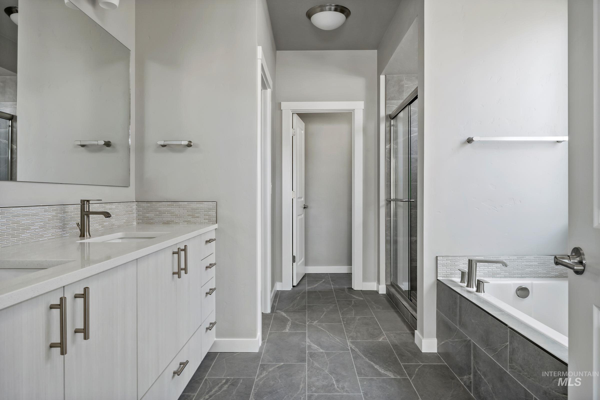 Bathroom with double vanity, a garden tub, a shower stall, and backsplash