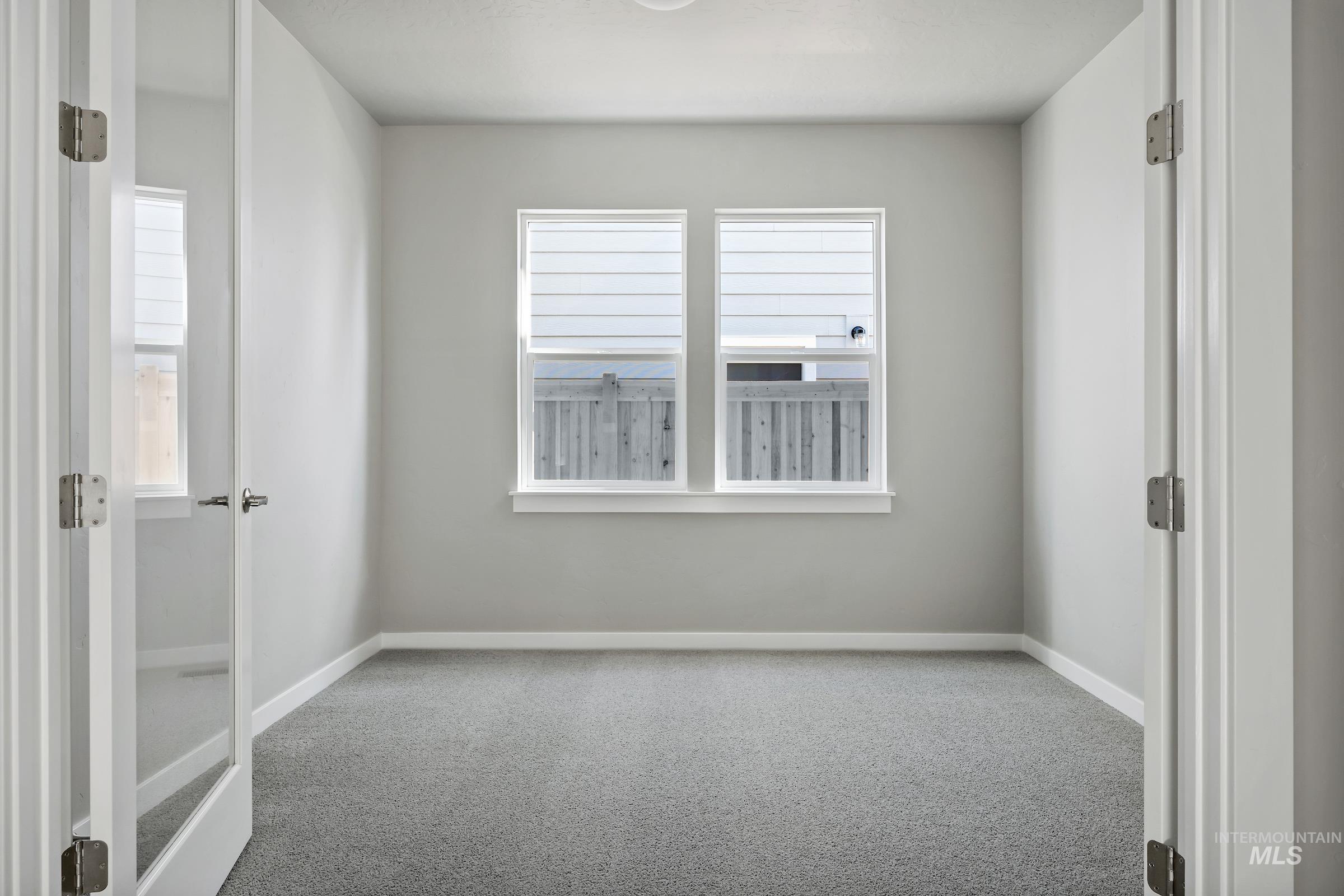 Carpeted spare room featuring baseboards