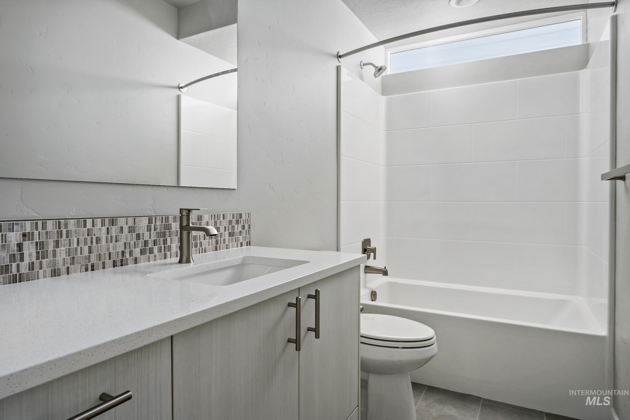 Full bathroom featuring vanity, bathtub / shower combination, decorative backsplash, and light tile patterned flooring
