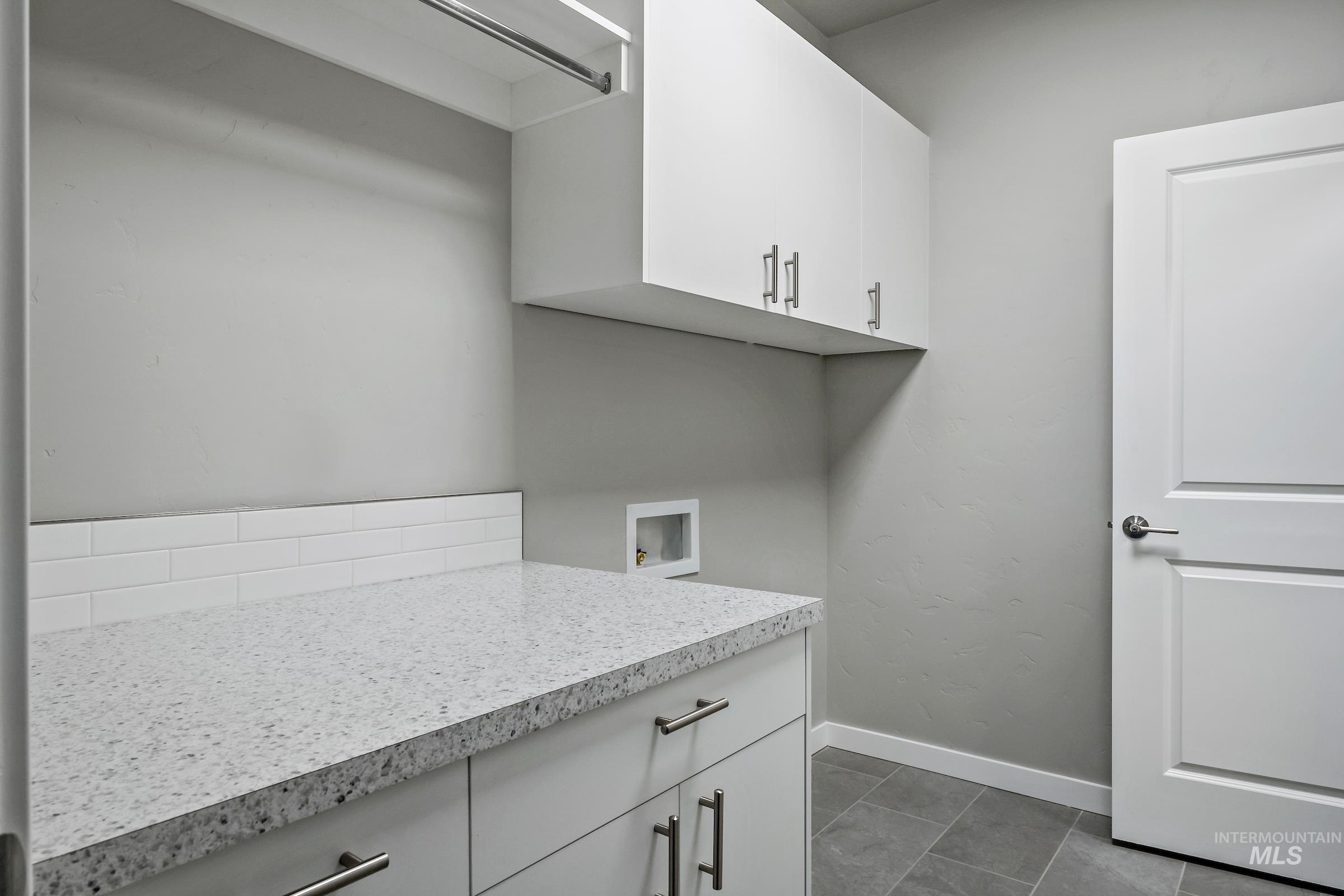 Laundry room featuring washer hookup and dark tile patterned flooring