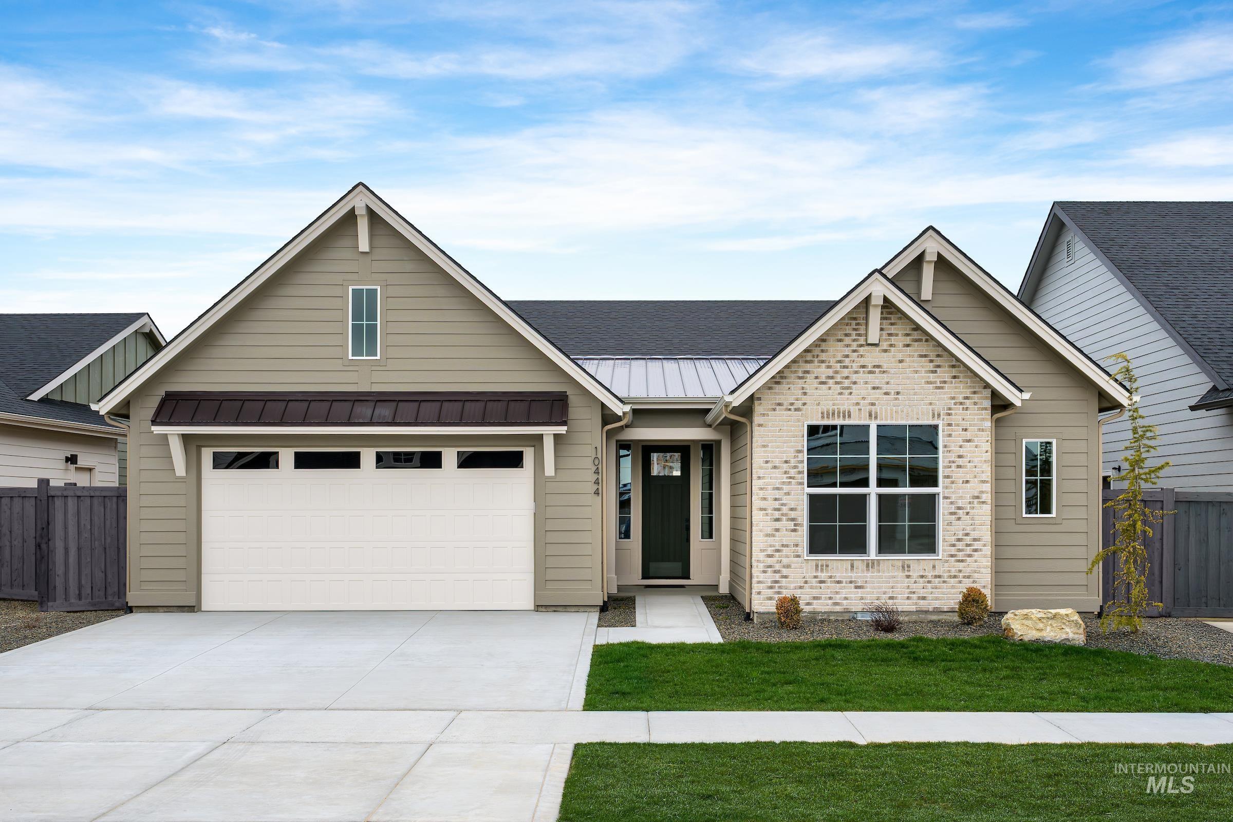 View of front of house with a metal roof, driveway, a standing seam roof, a garage, and a shingled roof