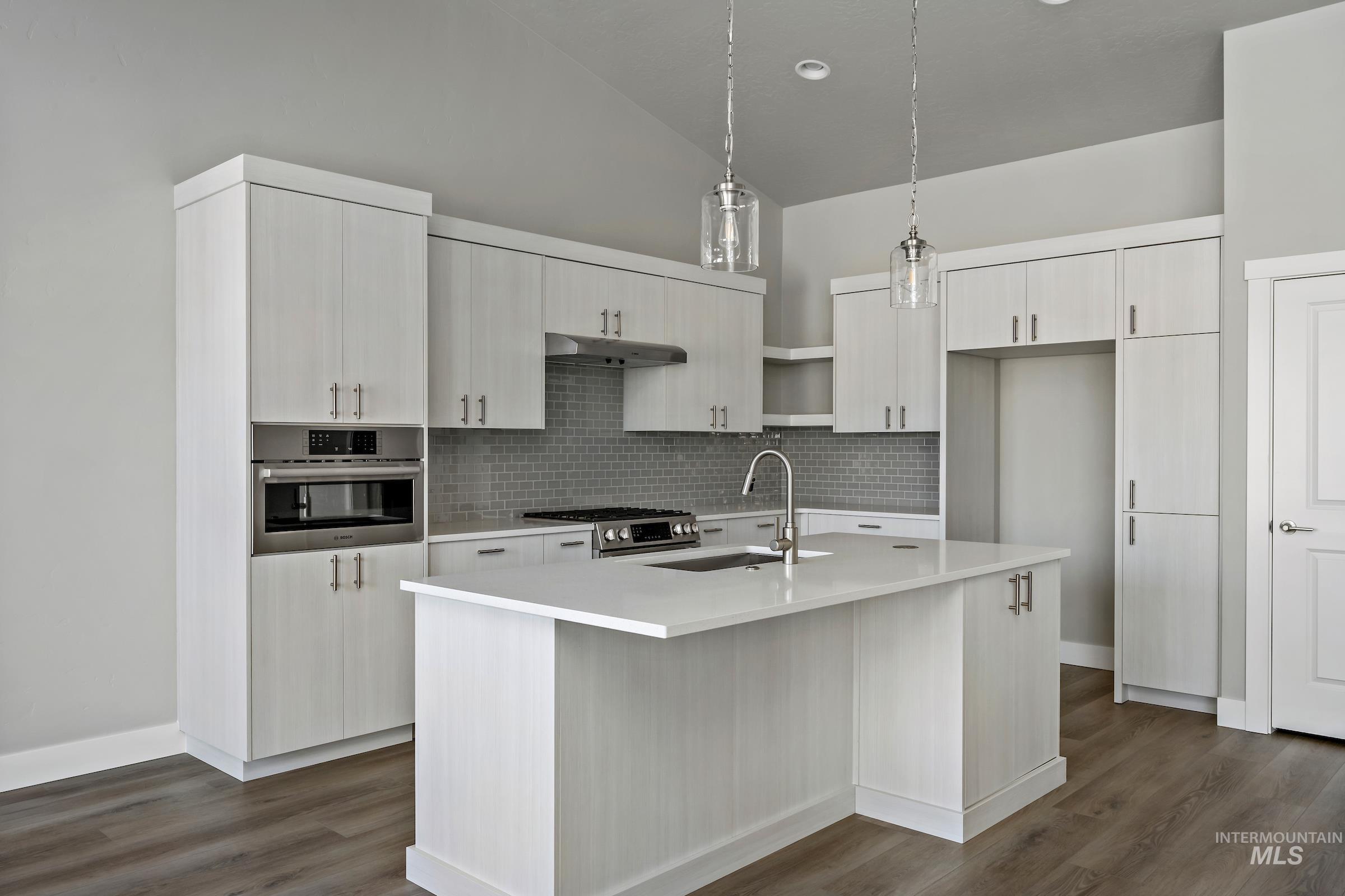 Kitchen featuring pendant lighting, stainless steel appliances, backsplash, an island with sink, and open shelves