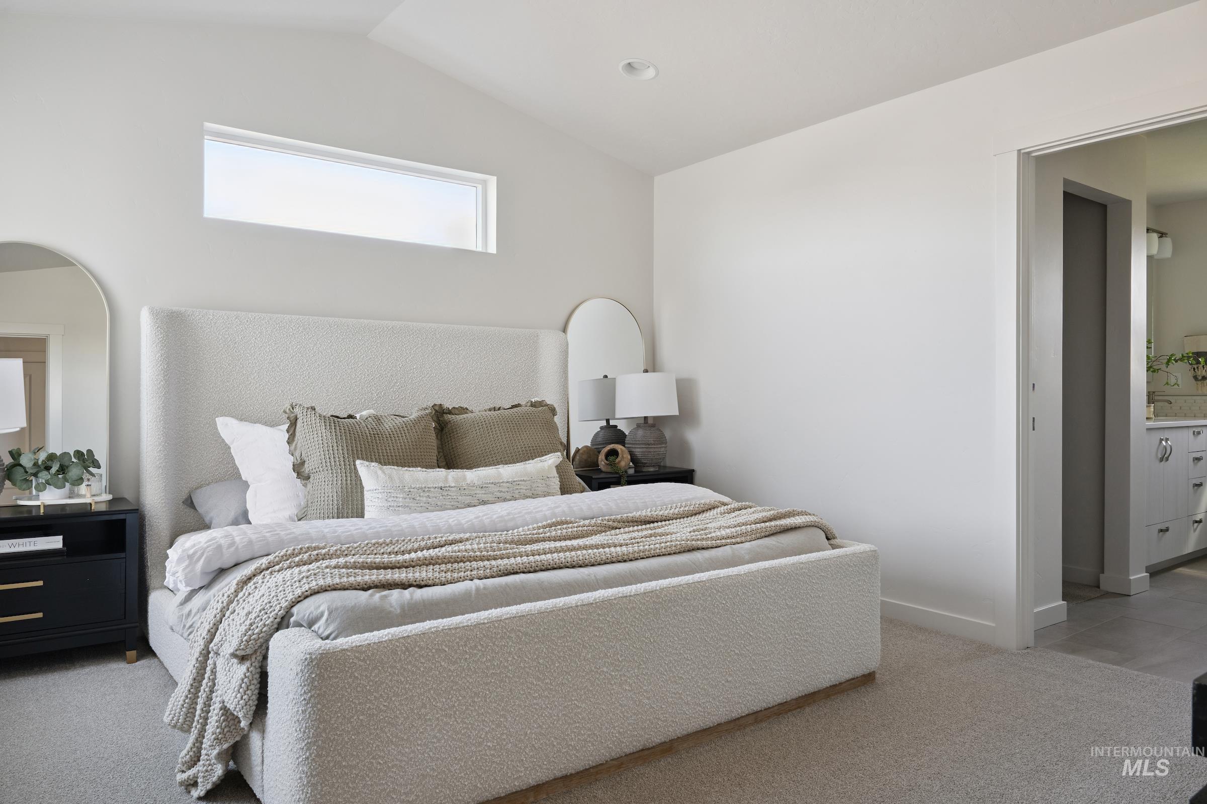 Bedroom with light colored carpet and vaulted ceiling