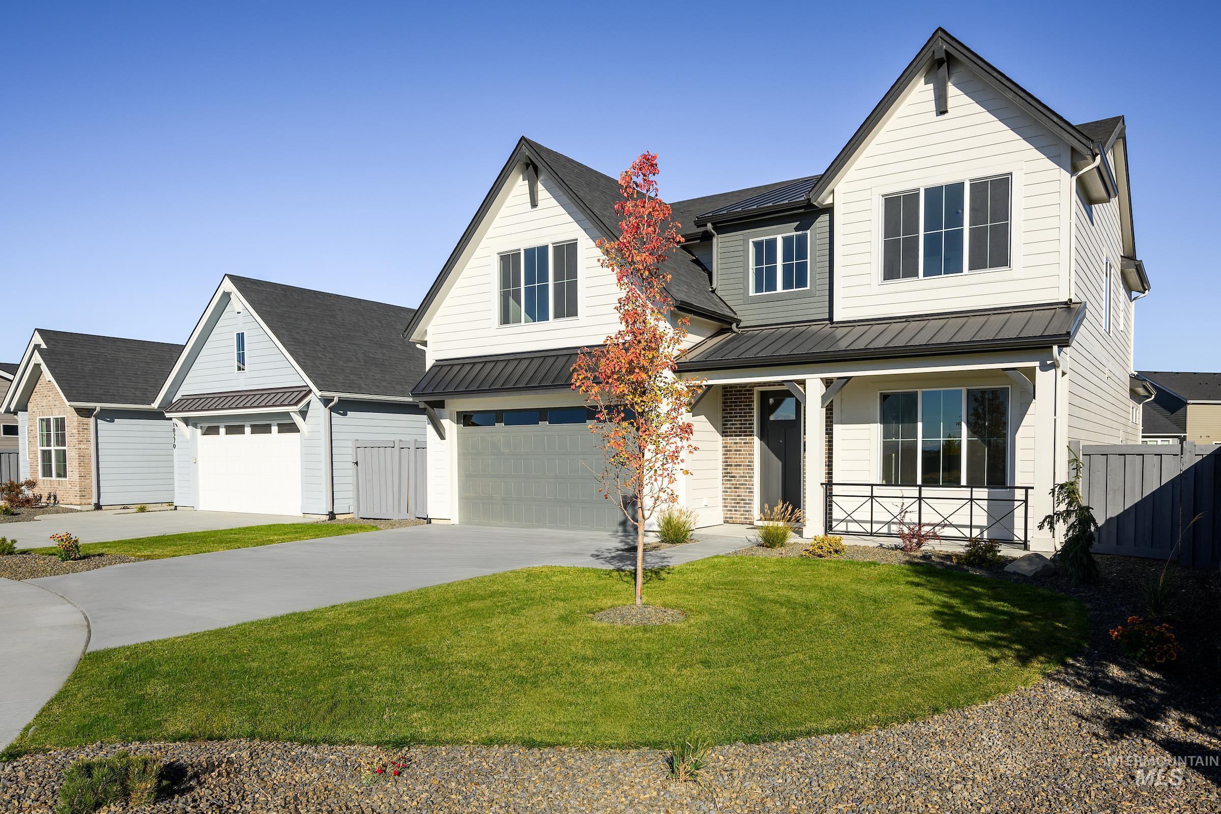 Modern farmhouse style home with a standing seam roof, a metal roof, a porch, concrete driveway, and an attached garage