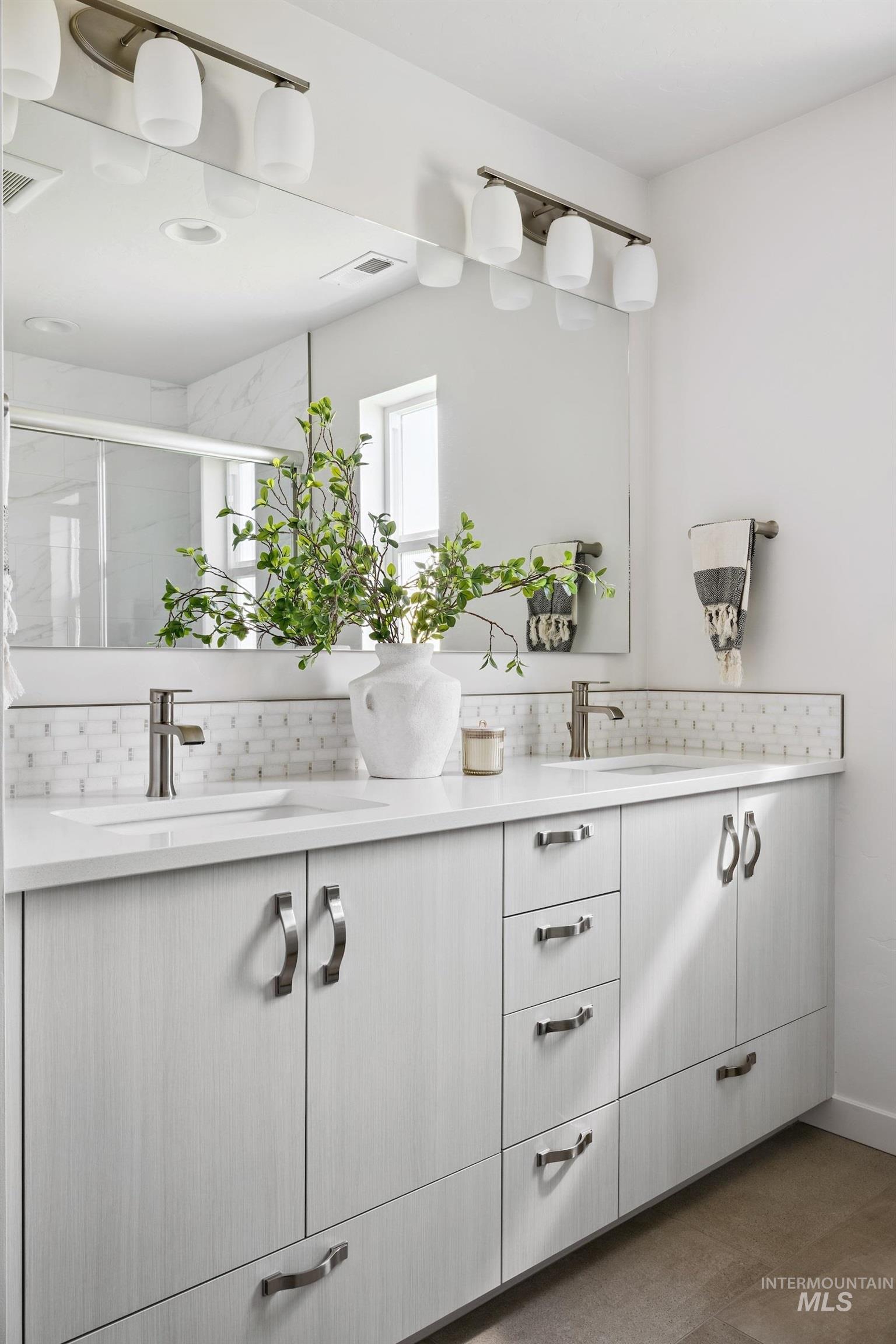 Full bath featuring a stall shower, double vanity, and decorative backsplash
