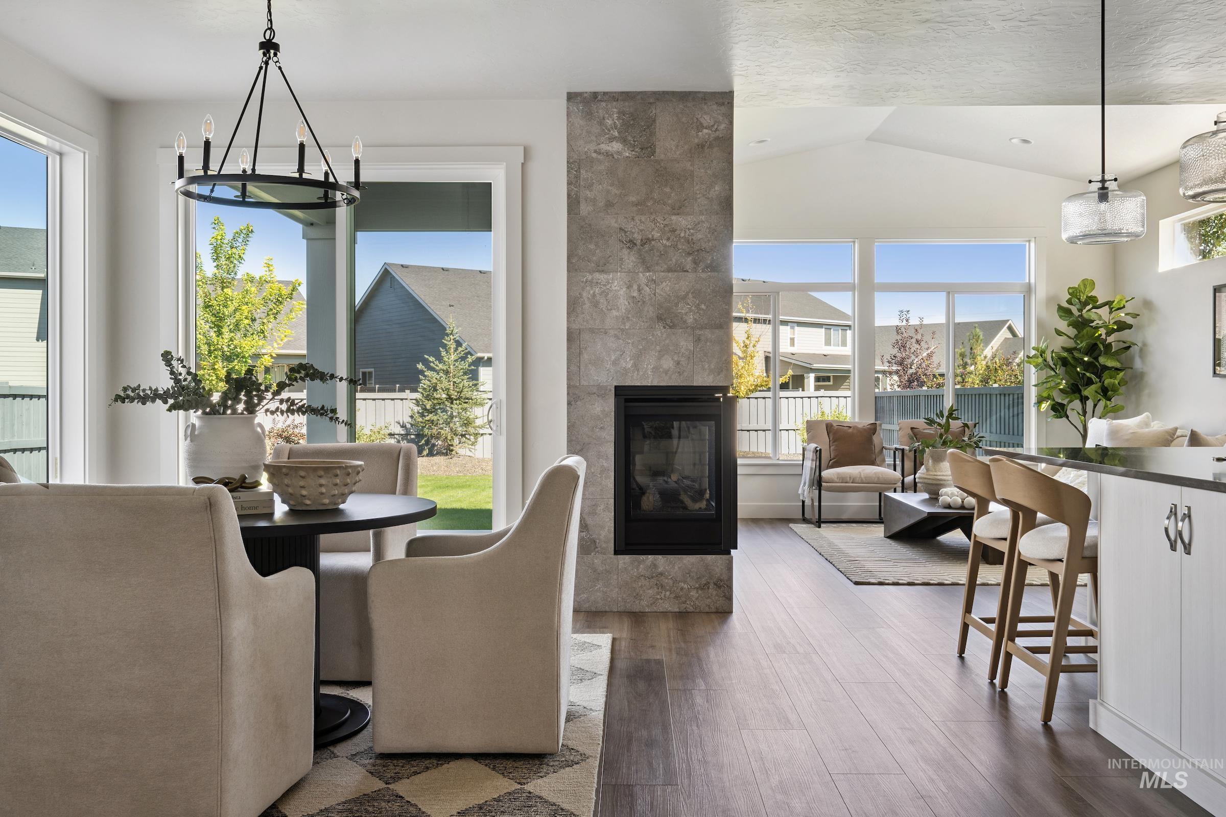 Dining room featuring dark wood-type flooring, lofted ceiling, a chandelier, and a fireplace