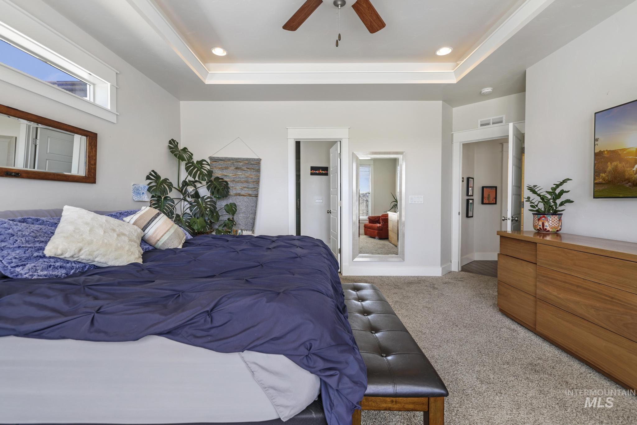 Bedroom featuring light carpet, a raised ceiling, a ceiling fan, ensuite bathroom, and recessed lighting