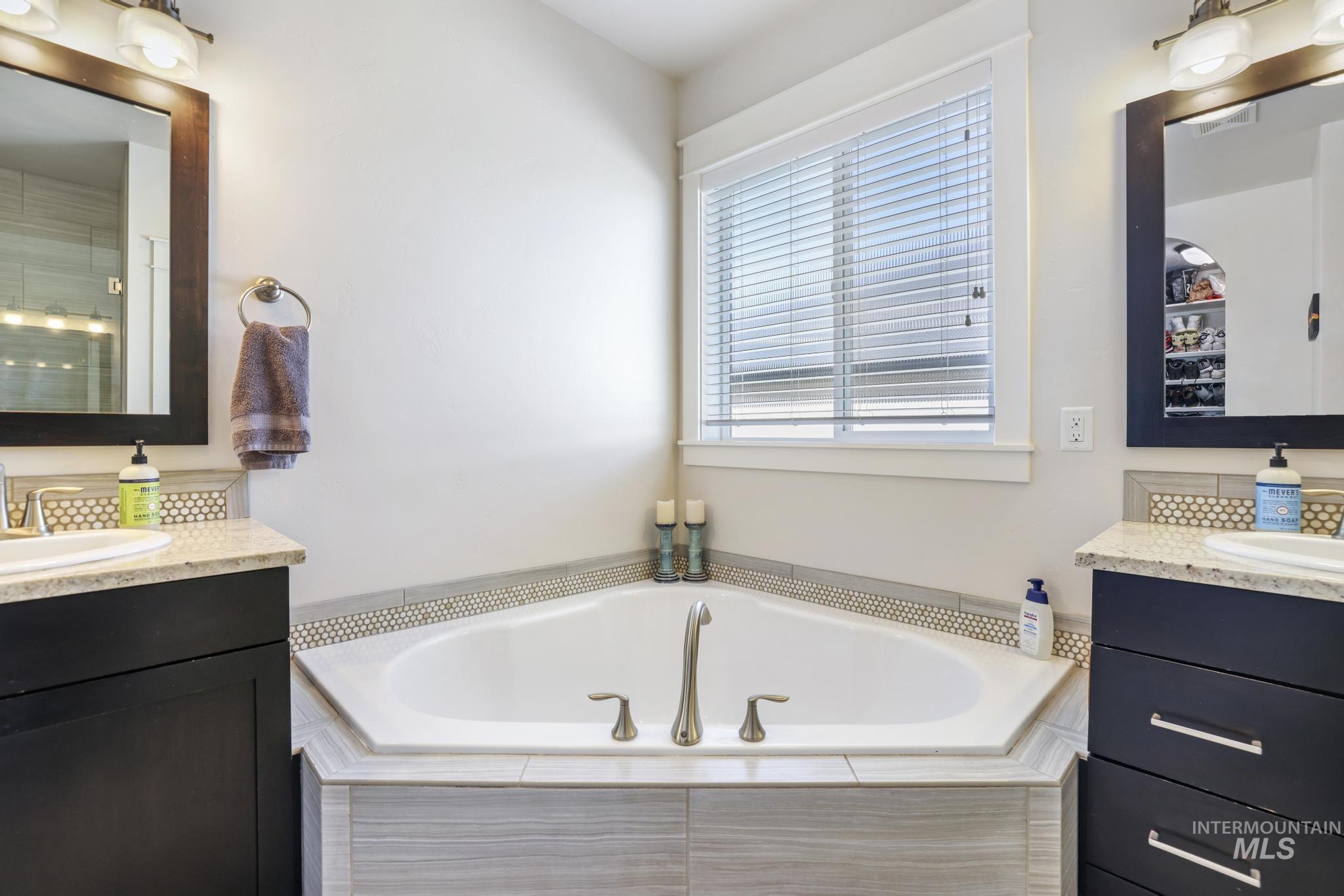 Full bathroom with two vanities, a bath, and a shower with shower door
