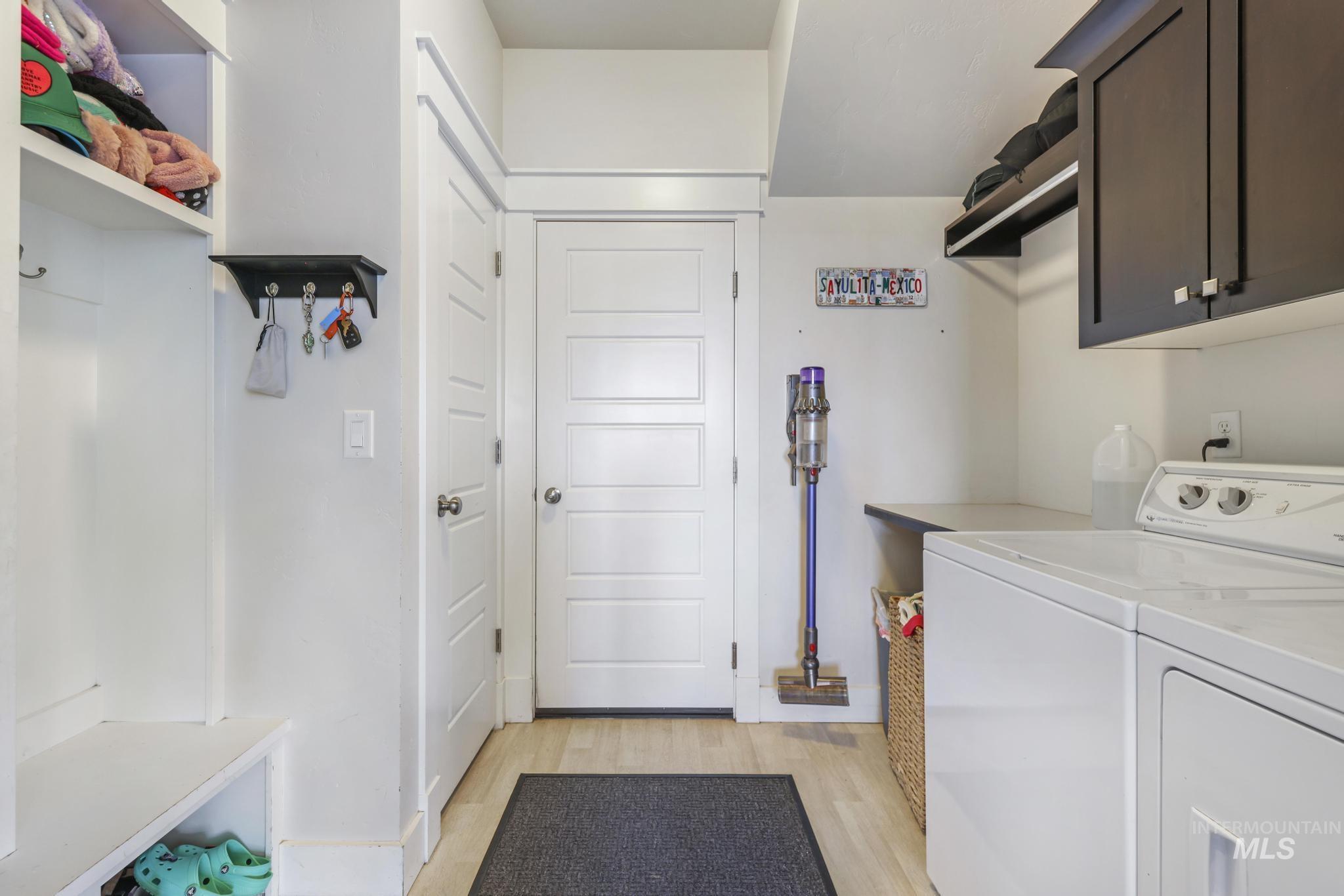 Washroom with light wood-type flooring, washer and dryer, and cabinet space