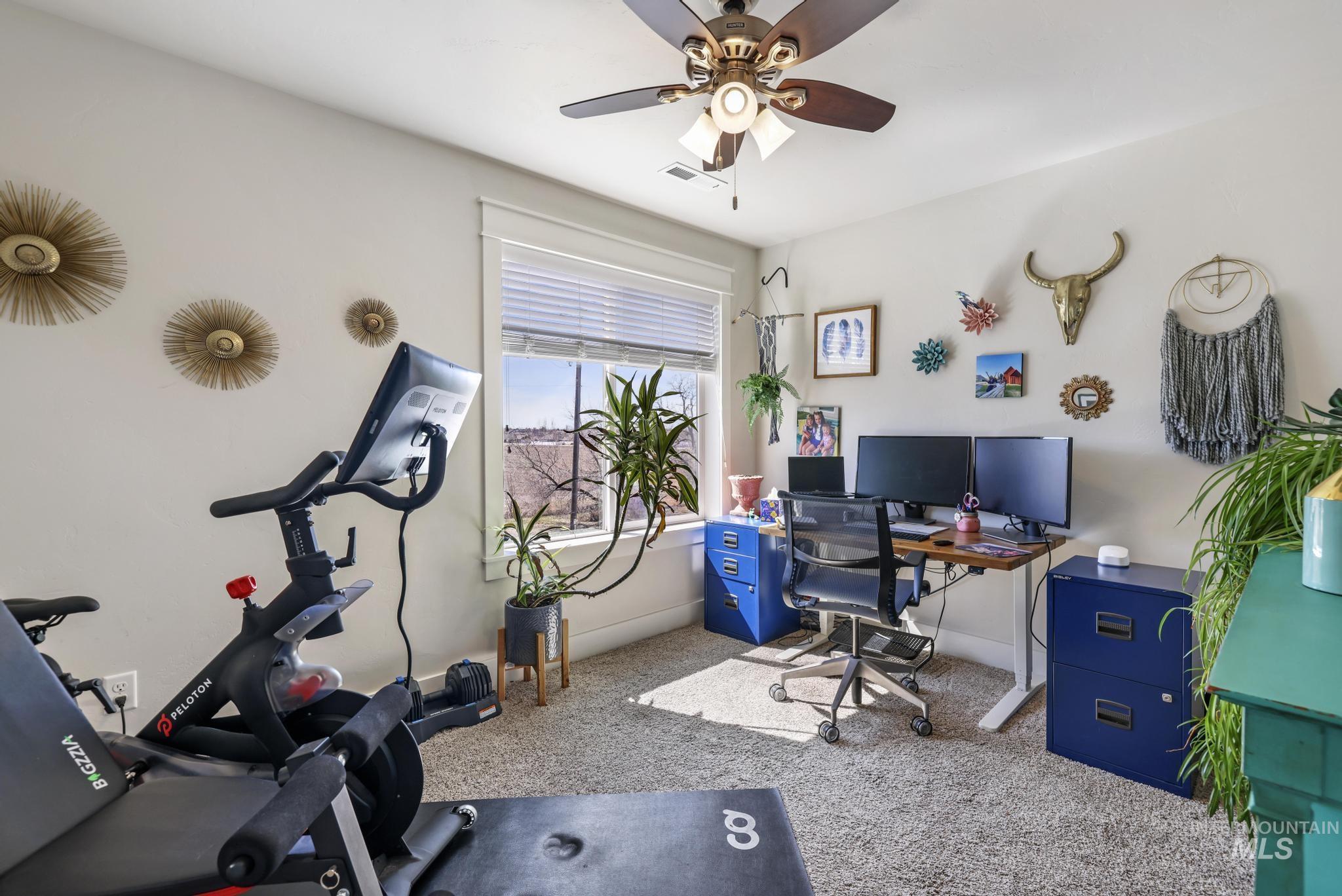 Home office featuring light carpet and a ceiling fan