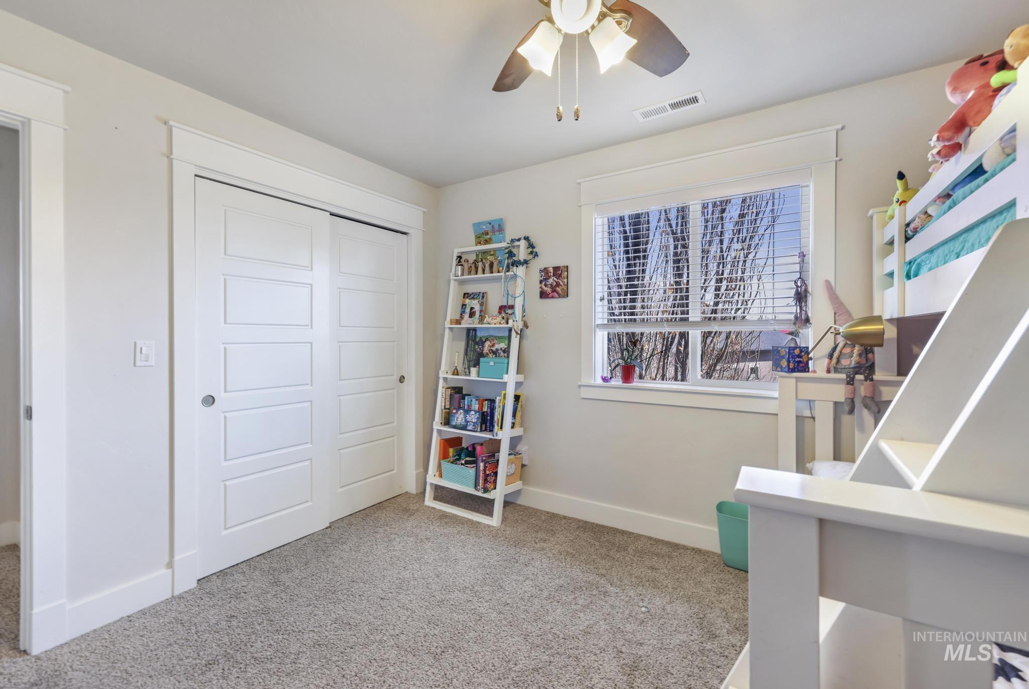 Bedroom with light colored carpet, a ceiling fan, and a closet