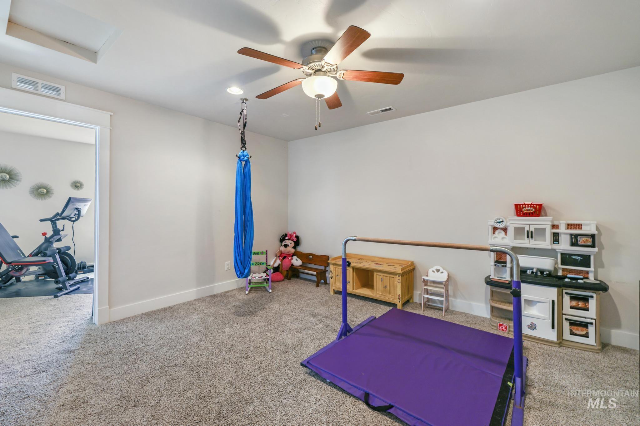 Workout area with attic access, carpet floors, and a ceiling fan