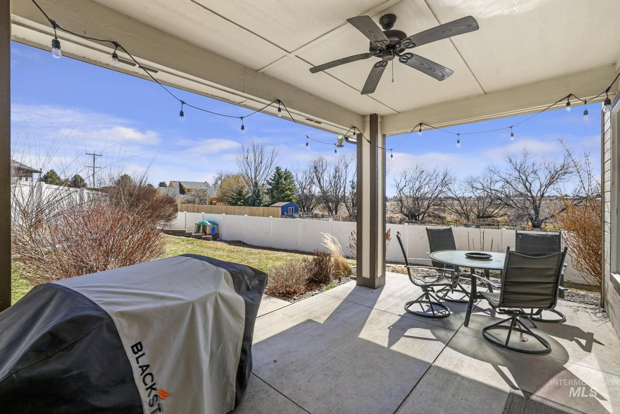 Fenced backyard with area for grilling, a patio, ceiling fan, and outdoor dining space