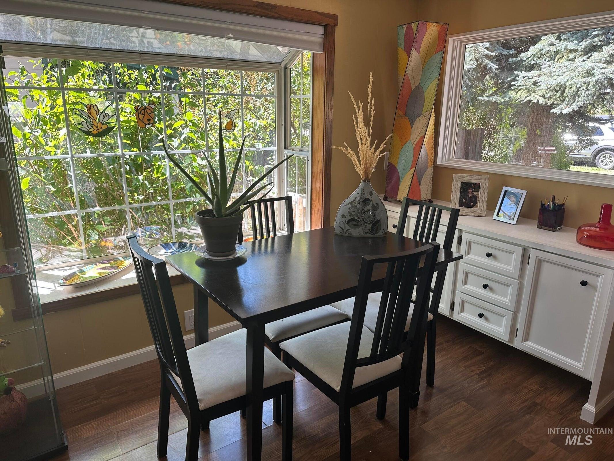 Dining room with dark wood-style flooring and baseboards