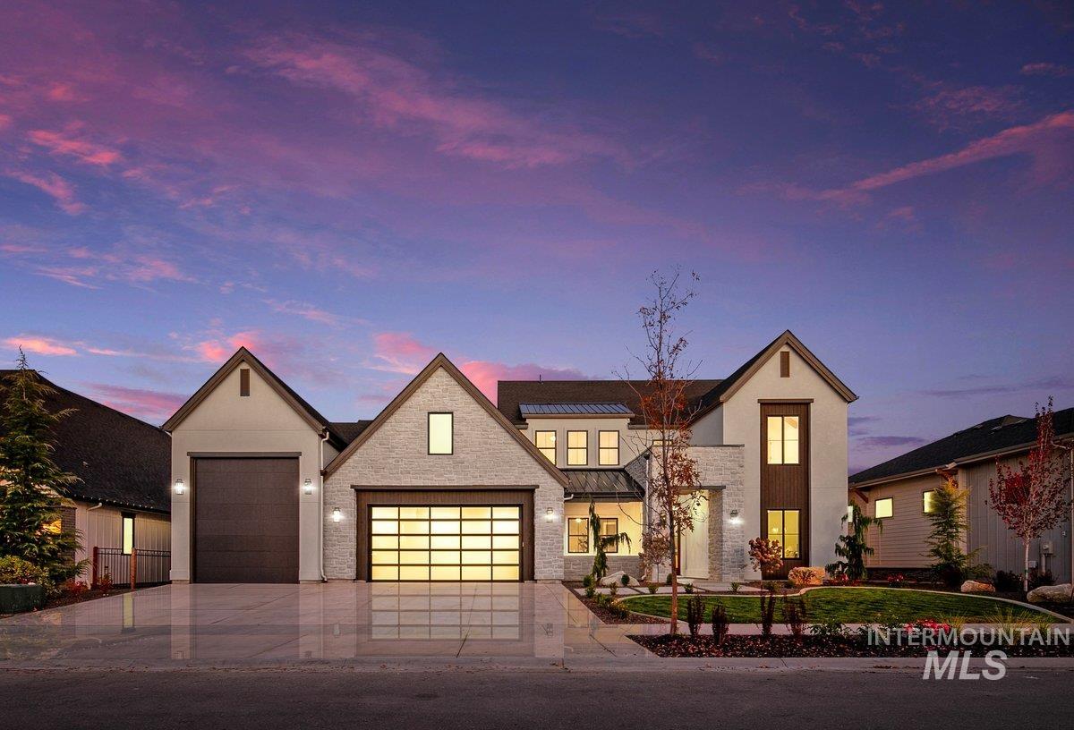 View of front of home featuring driveway, a garage, a standing seam roof, a metal roof, and stone siding