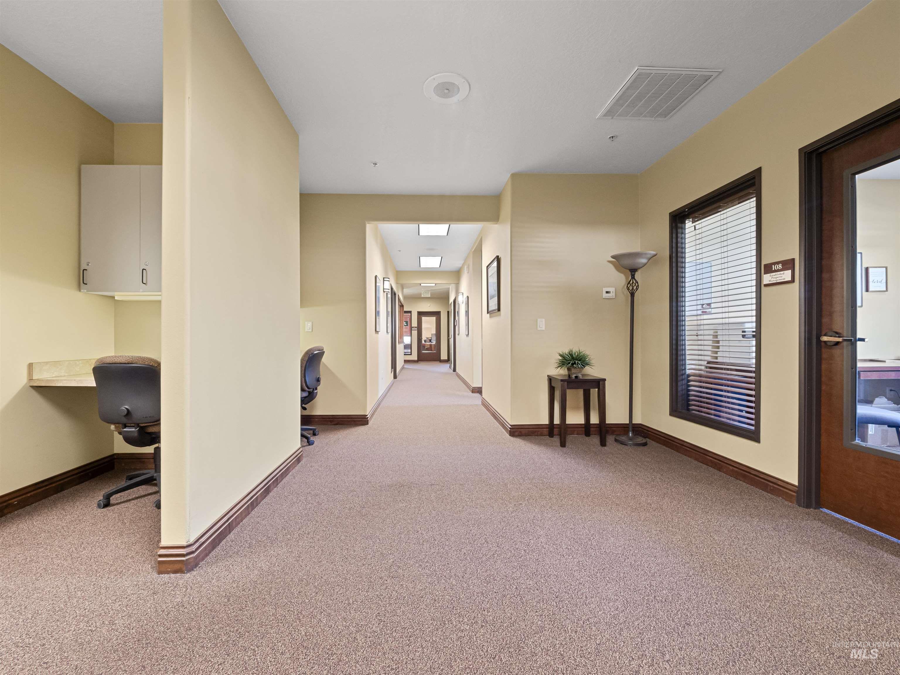 Corridor with light carpet and an office area