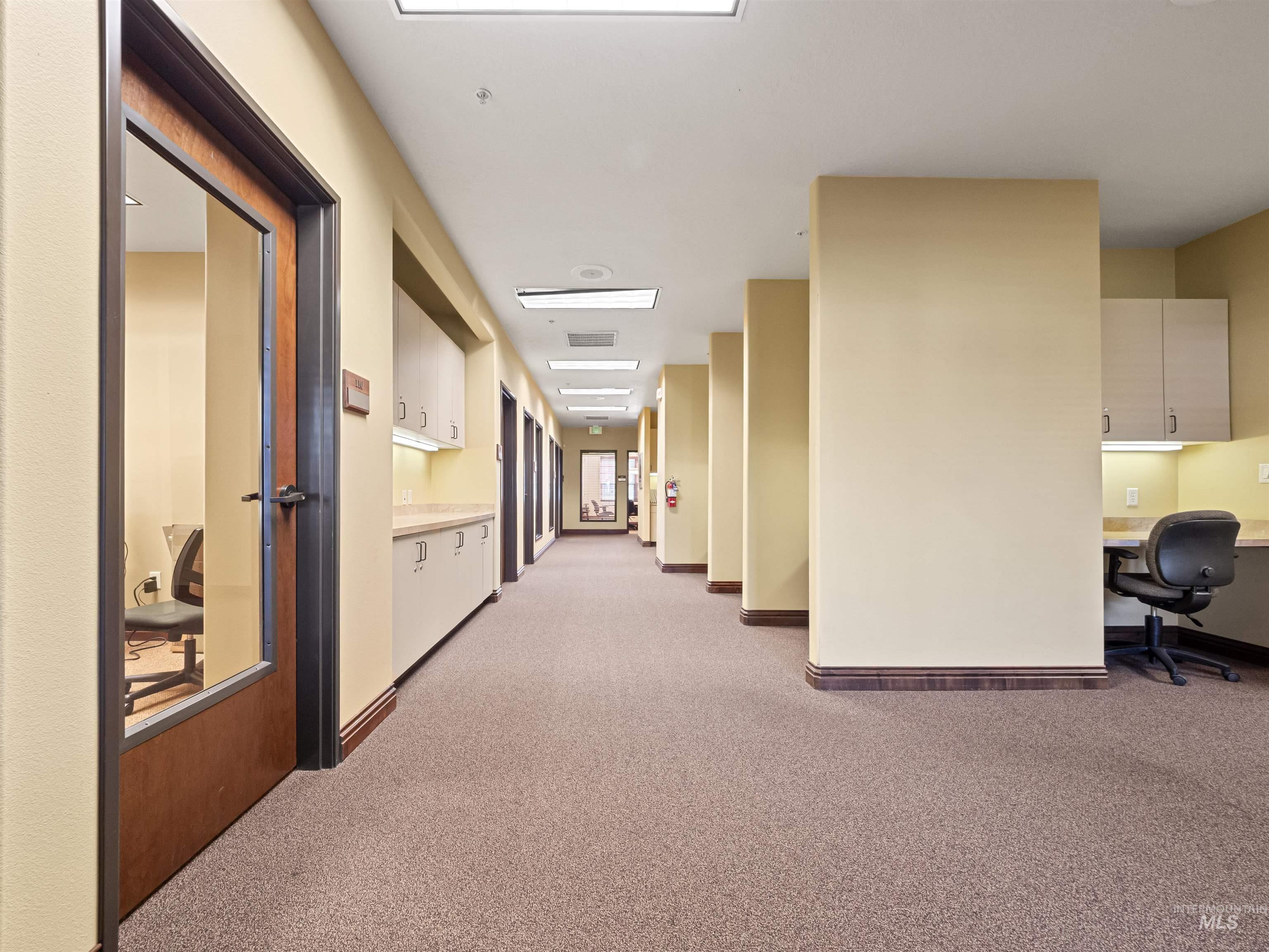 Hallway featuring light colored carpet and an office area