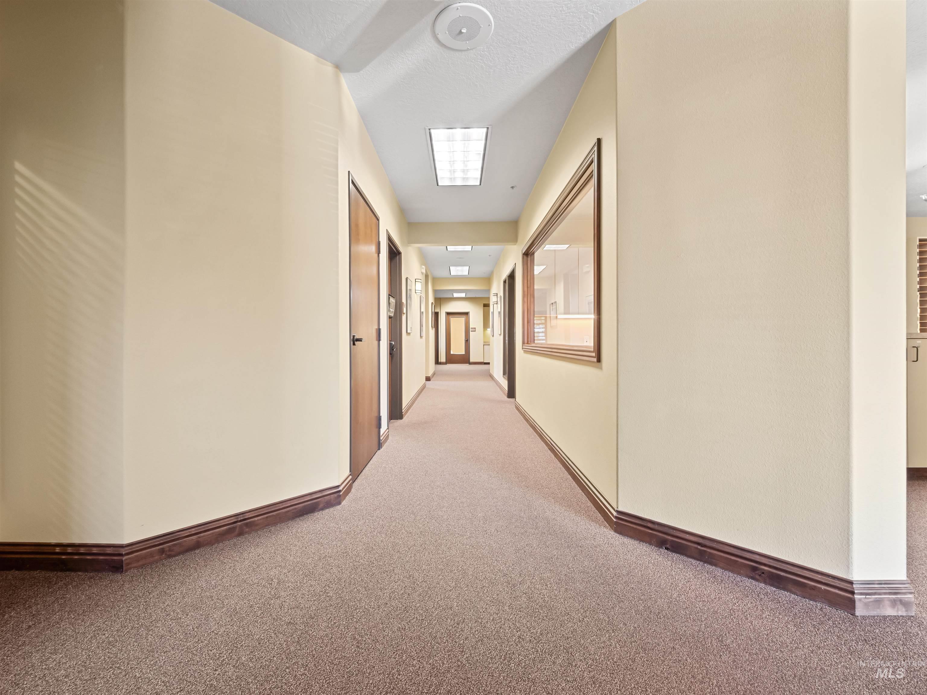 Corridor featuring carpet flooring and baseboards