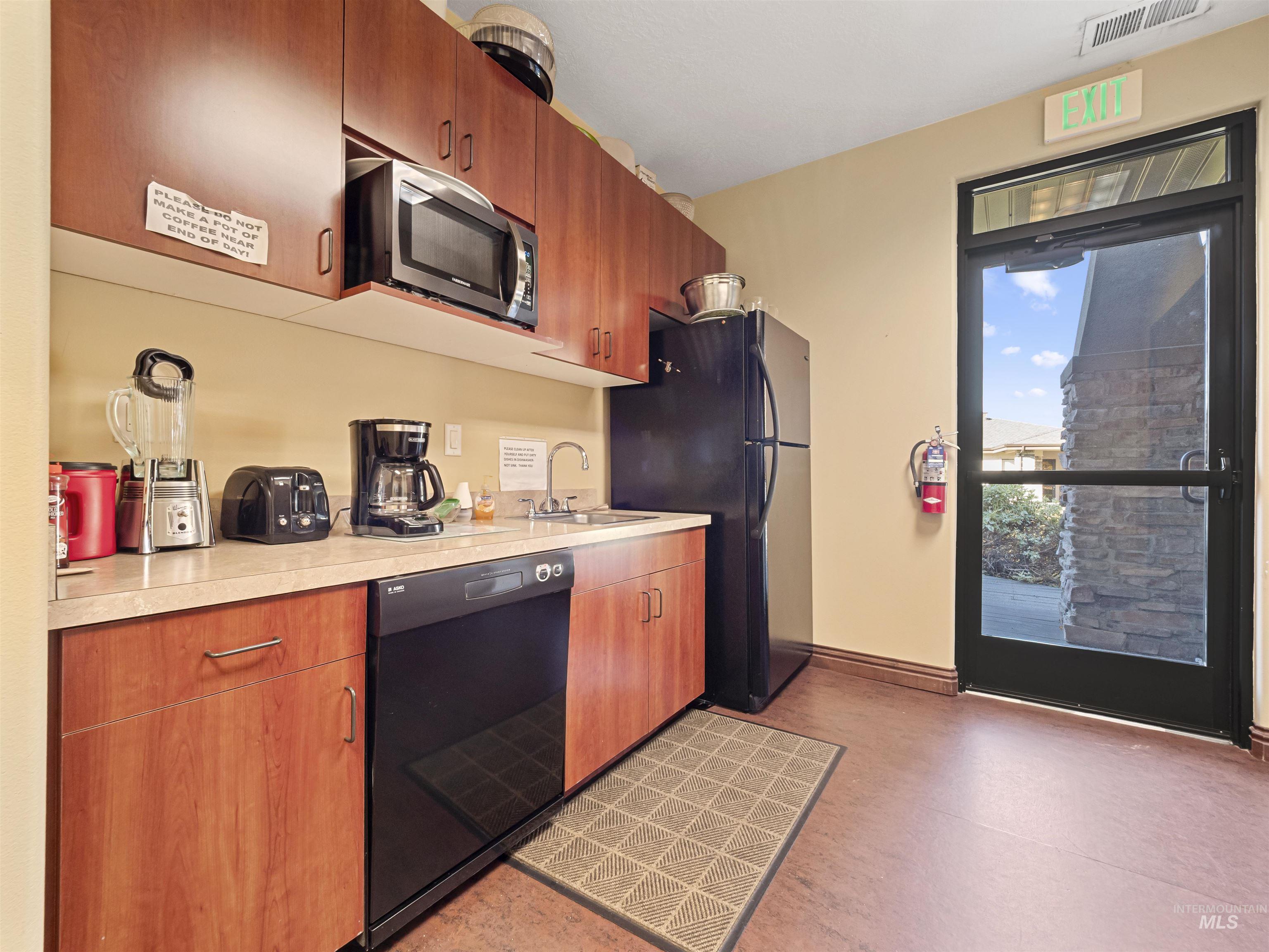 Kitchen featuring black appliances, light countertops, brown cabinetry, and modern cabinets