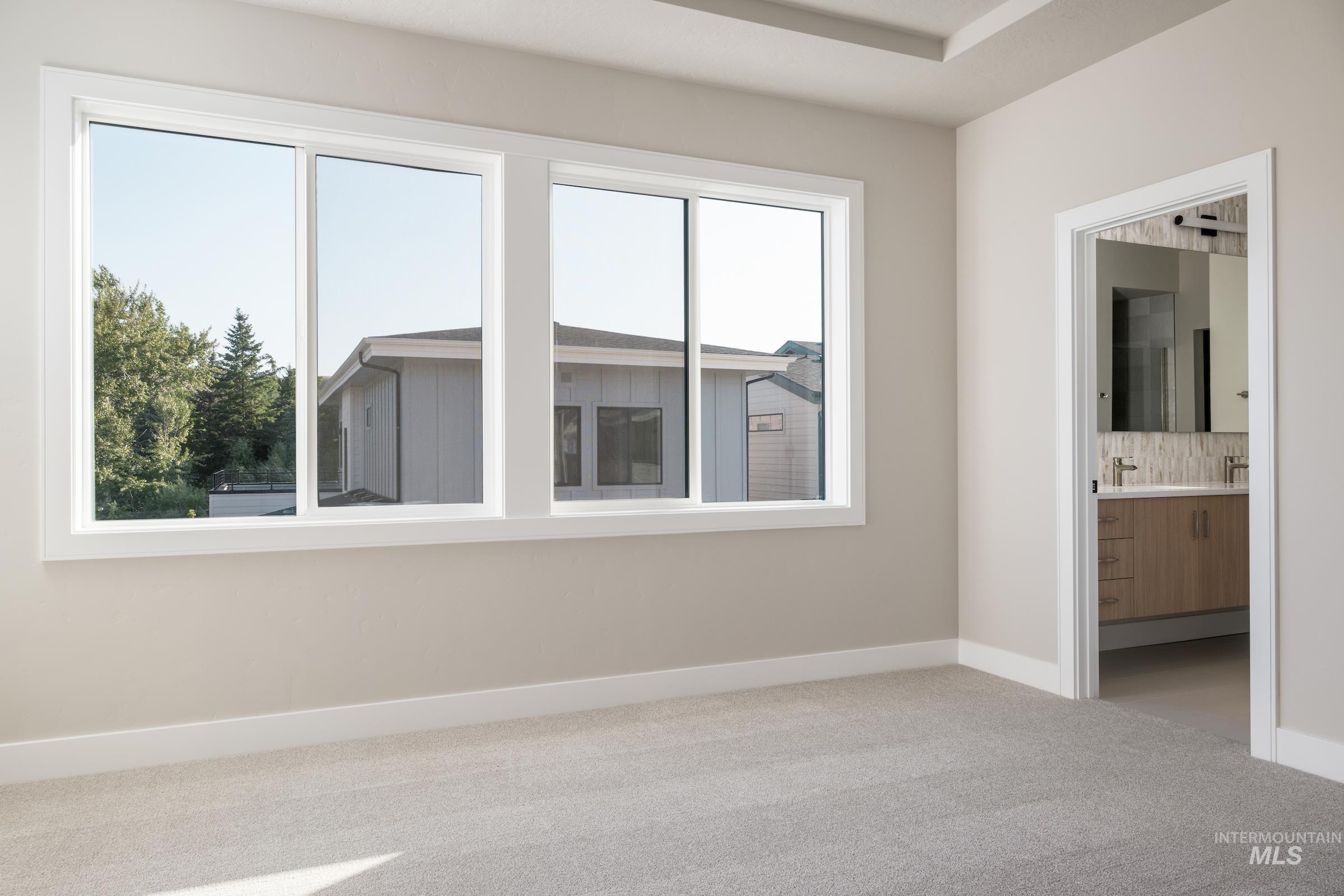 Unfurnished bedroom featuring ensuite bath and light carpet