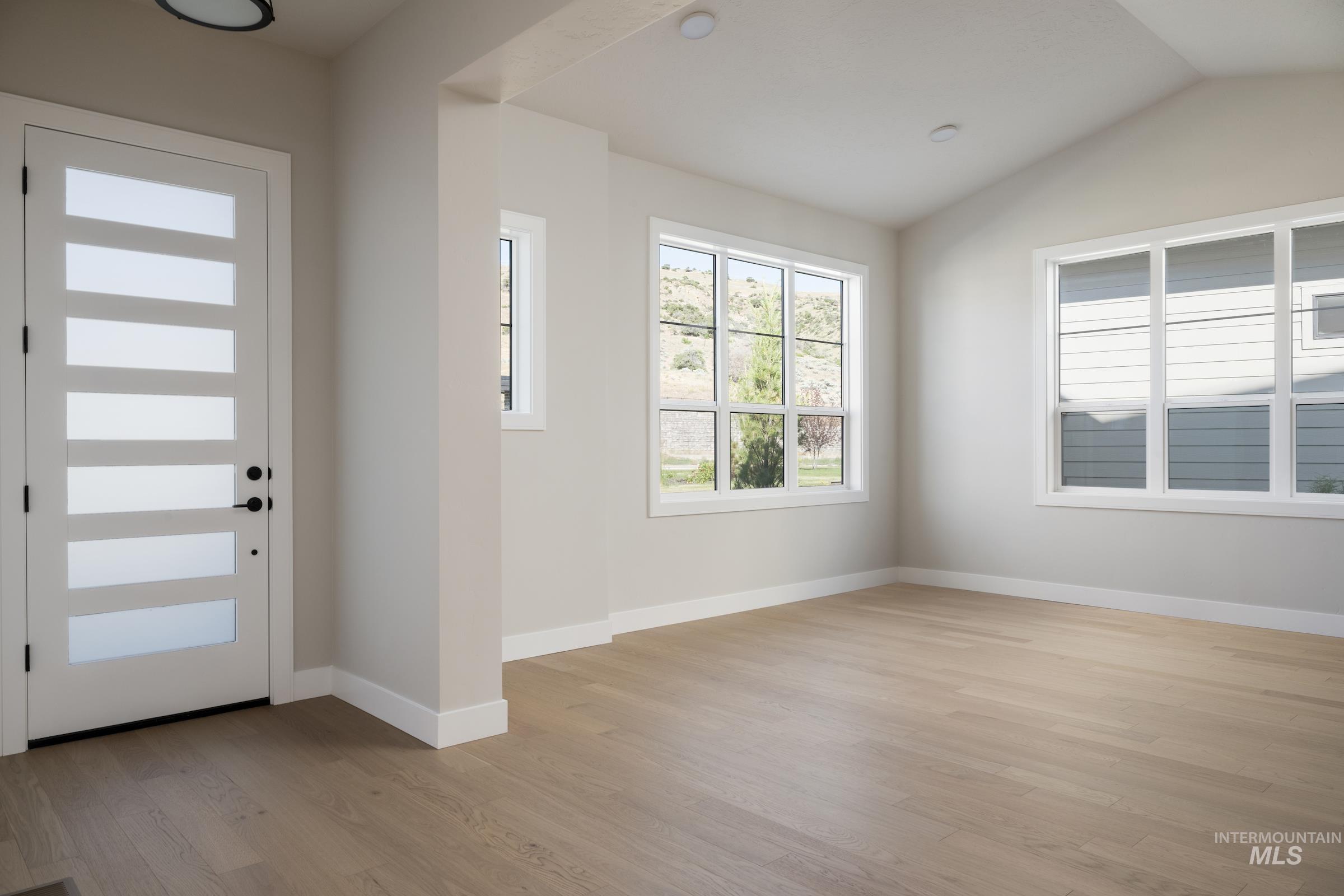 Foyer entrance with light wood-style floors and lofted ceiling