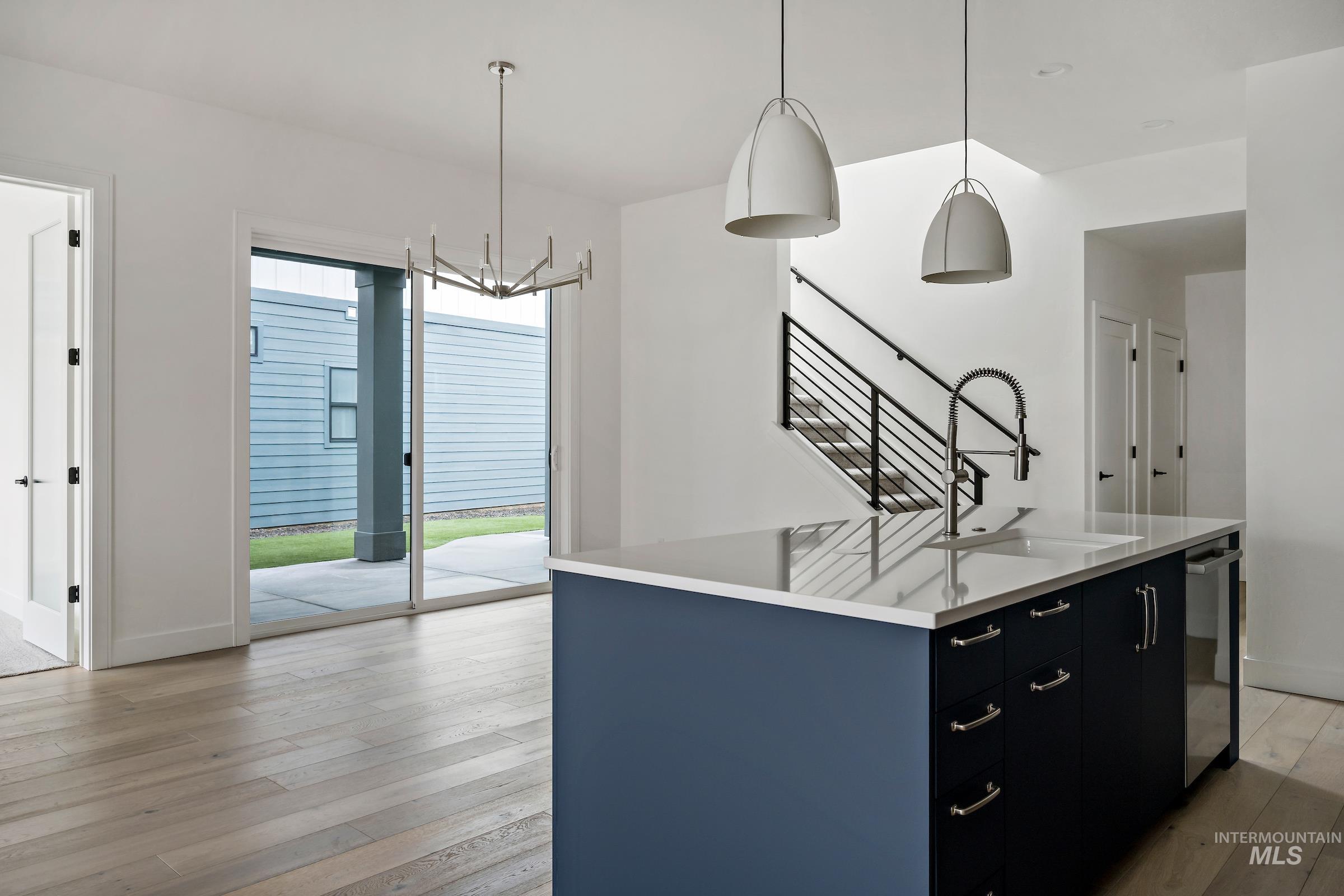 Kitchen with hanging light fixtures, light wood-type flooring, dark cabinets, and a chandelier