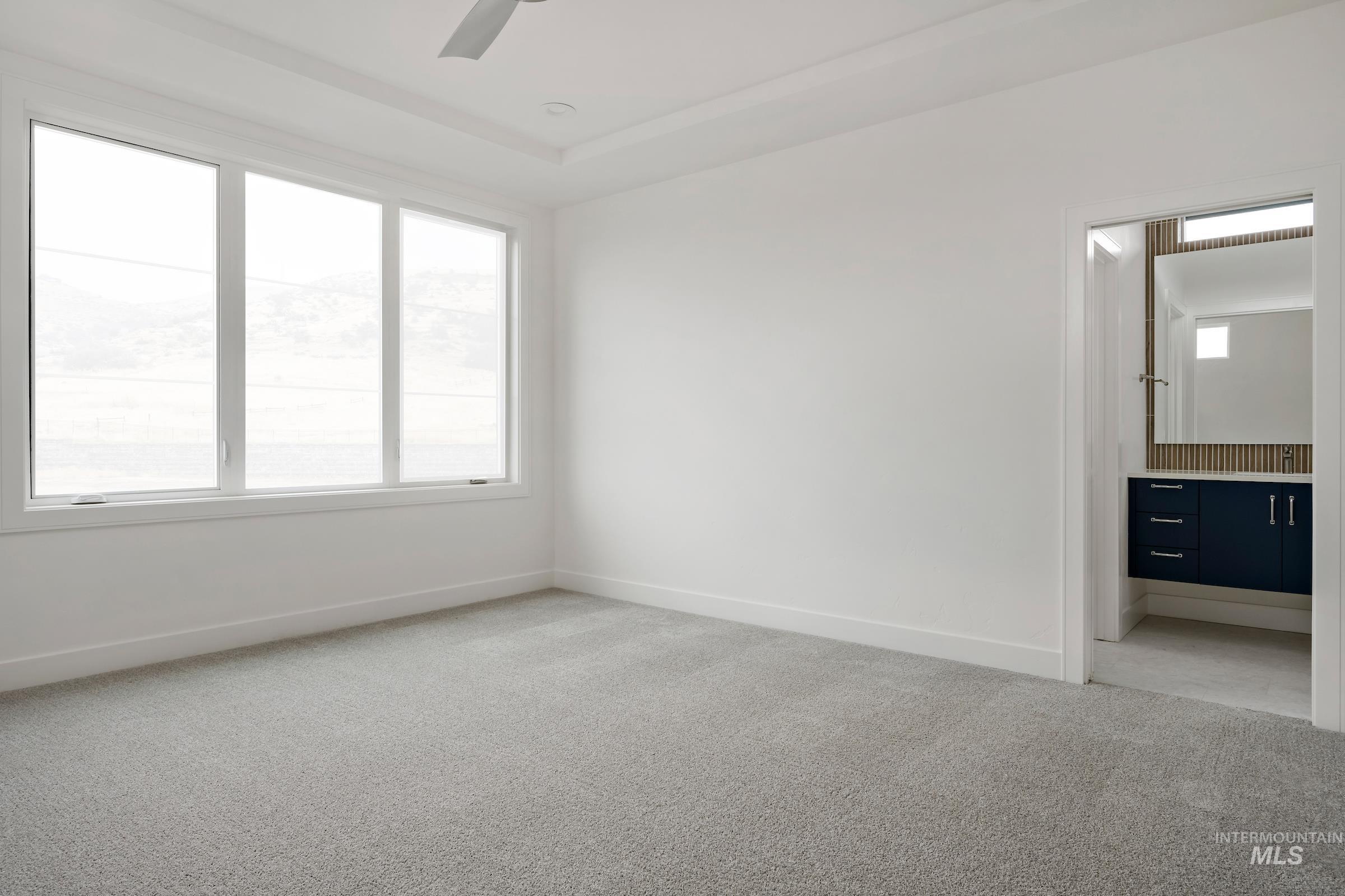 Unfurnished bedroom with light colored carpet, connected bathroom, and ceiling fan