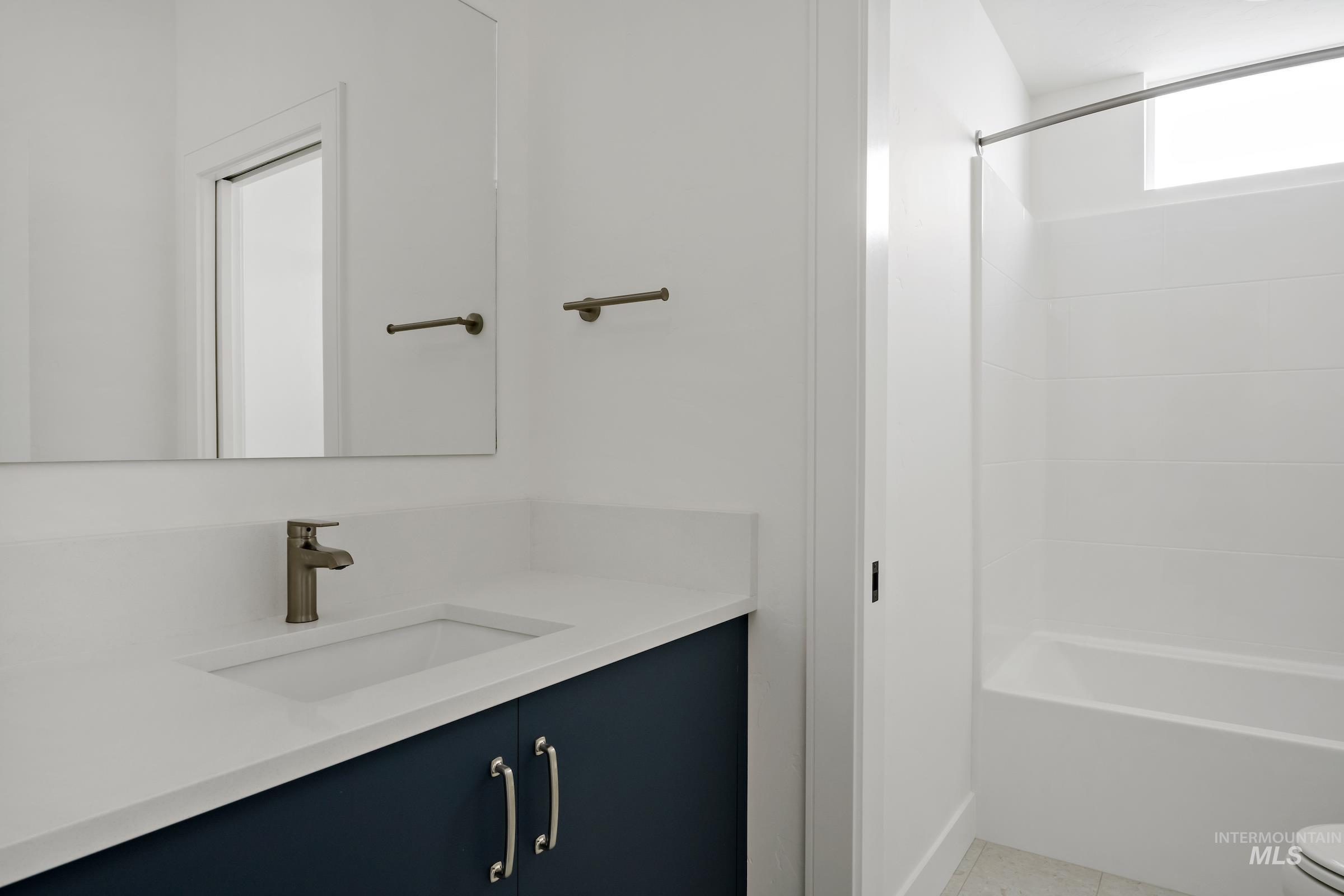 Bathroom featuring vanity, light tile patterned floors, and shower / washtub combination