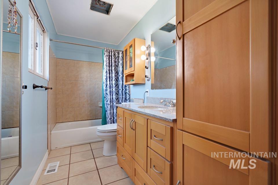 Bathroom with vanity, light tile patterned floors, and shower / bath combo with shower curtain