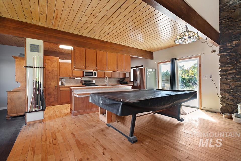 Game room featuring light wood-style flooring and a wood ceiling with exposed beams