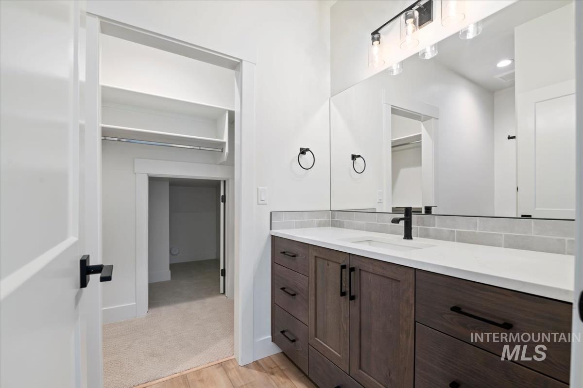 Bathroom featuring vanity, light wood finished floors, tasteful backsplash, and recessed lighting