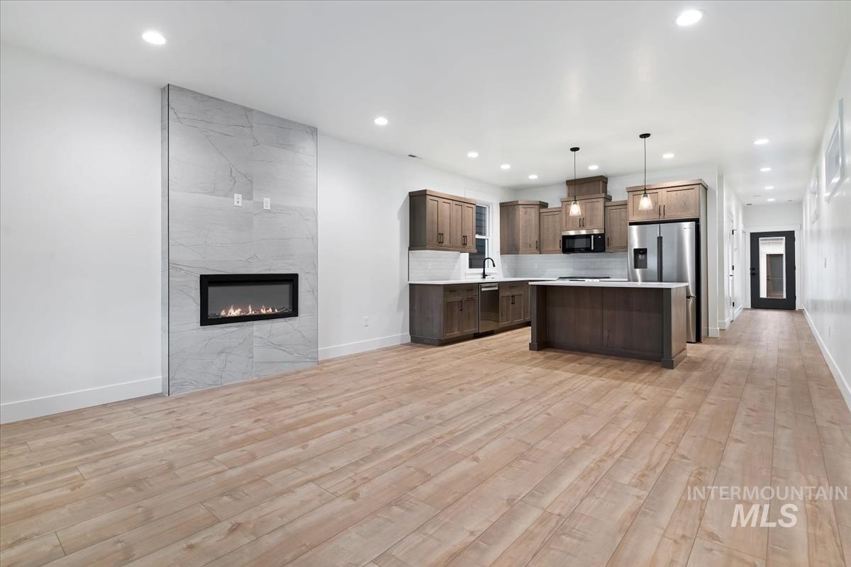 Kitchen with open floor plan, light countertops, decorative light fixtures, a premium fireplace, and tasteful backsplash