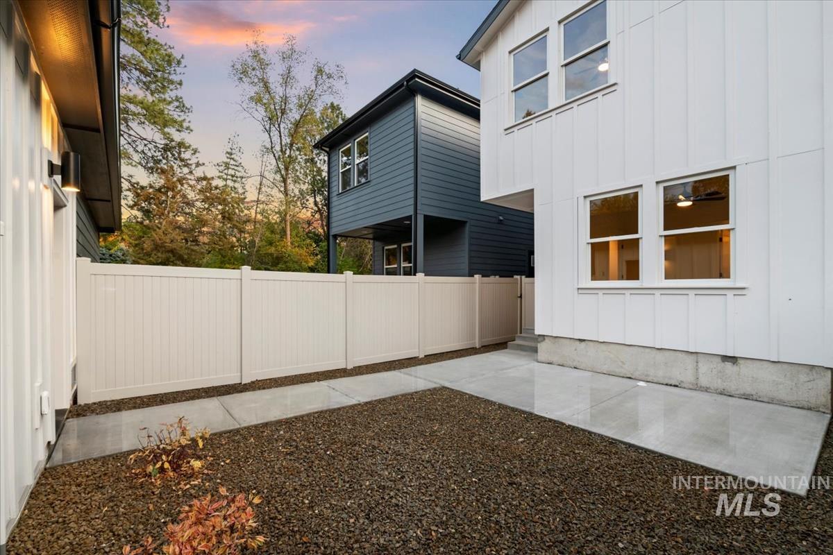 View of side of property with board and batten siding, a fenced backyard, and a patio