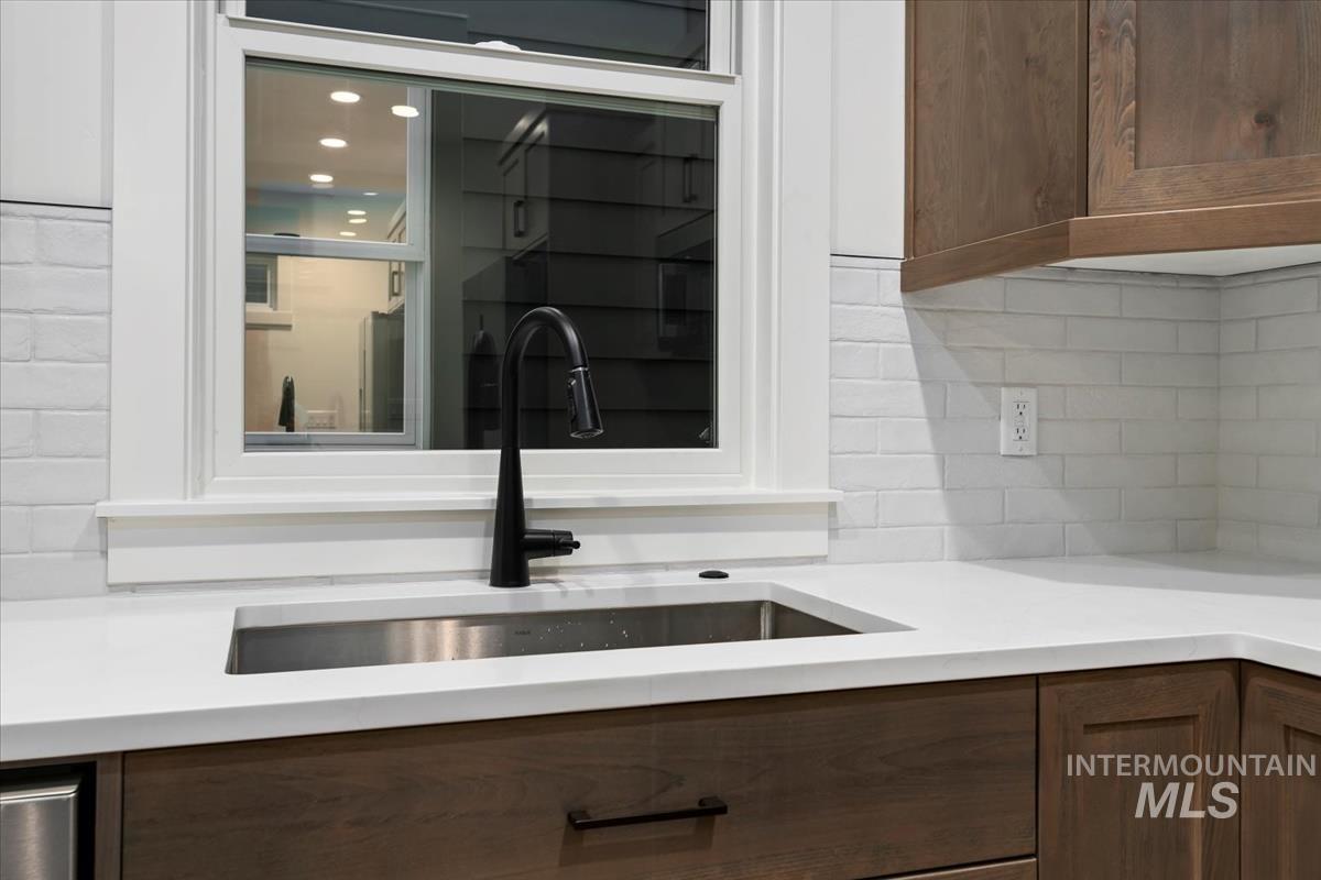 Kitchen view of tasteful backsplash, dark brown cabinetry, and light stone counters