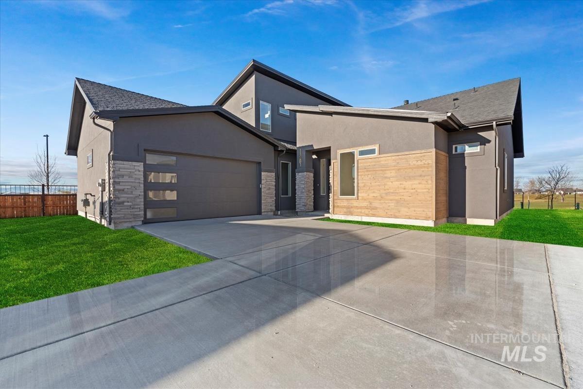 Contemporary house featuring stucco siding, stone siding, concrete driveway, and an attached garage