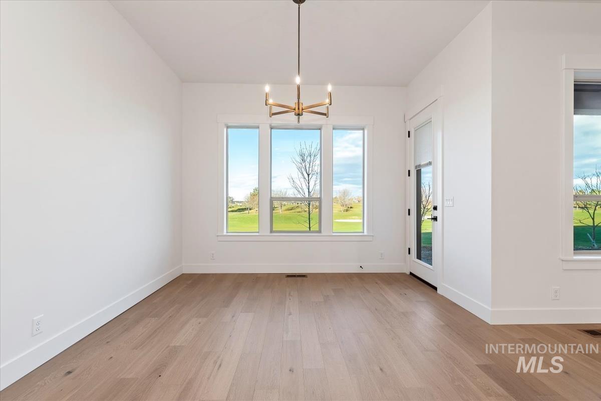 Unfurnished dining area with a chandelier and light wood-type flooring