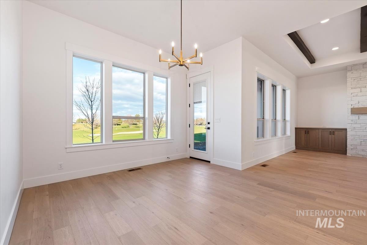 Unfurnished dining area with a raised ceiling, light wood-style flooring, a chandelier, and recessed lighting