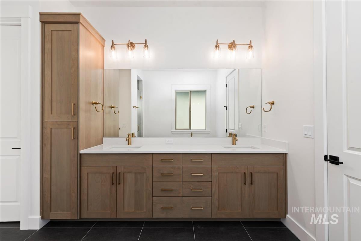 Bathroom with double vanity and dark tile patterned flooring
