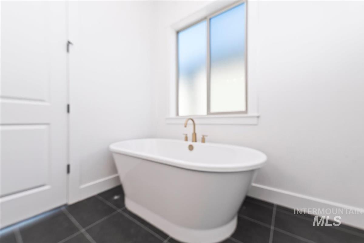 Bathroom with a freestanding tub and dark tile patterned flooring