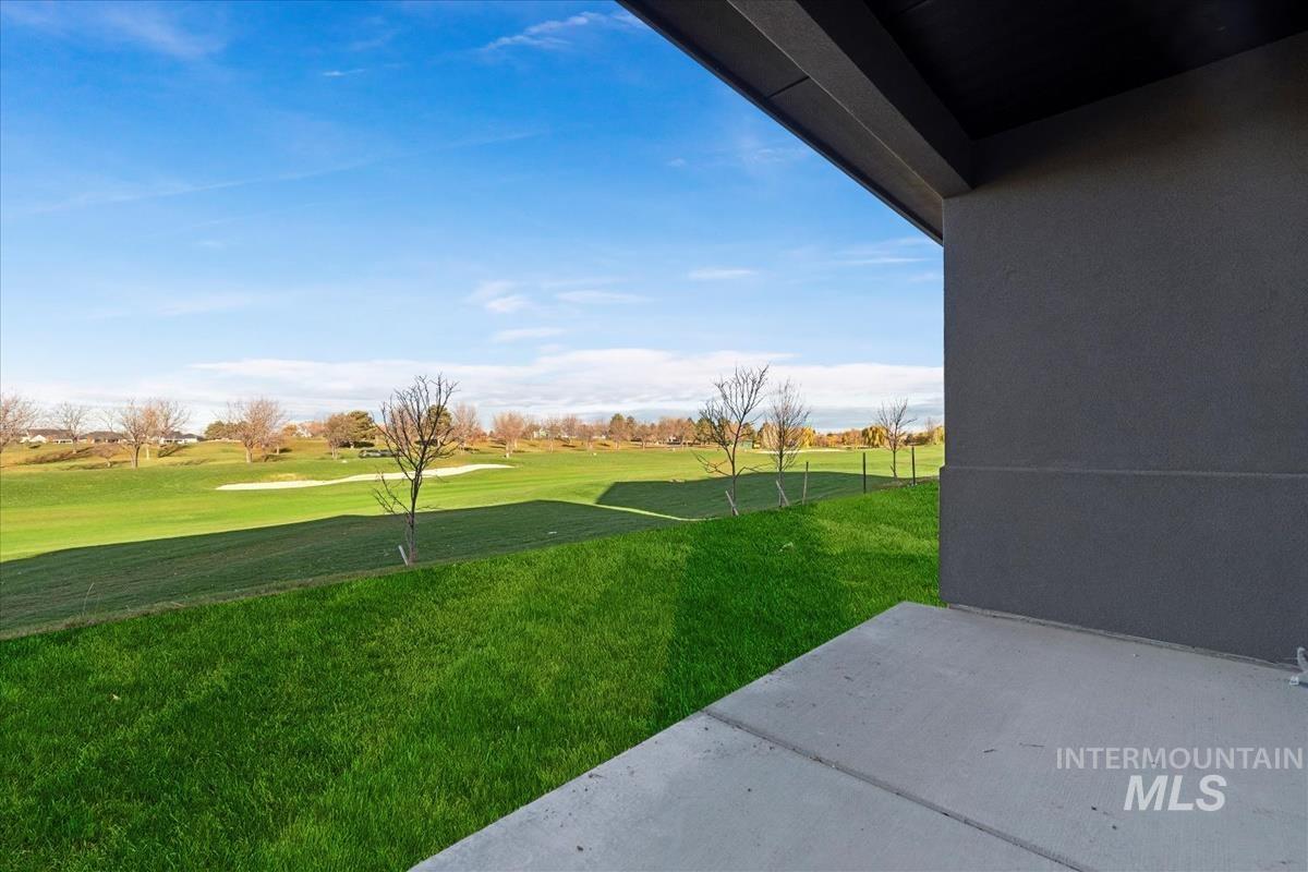 View of green lawn with a patio and golf course view