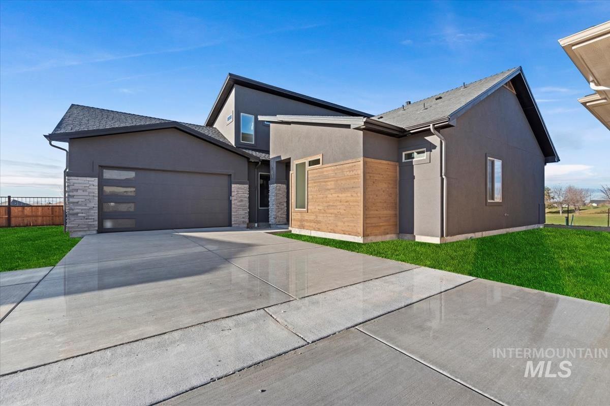 Contemporary home with stucco siding, driveway, stone siding, and an attached garage