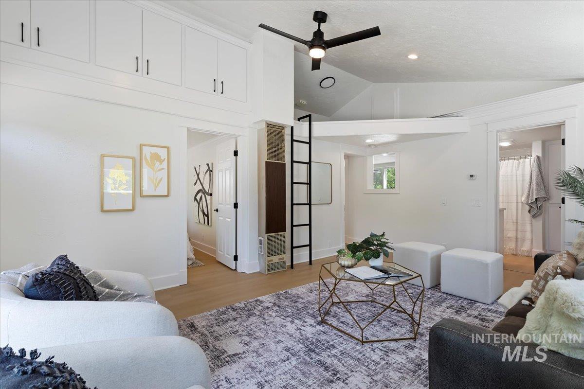 Living room featuring wood finished floors, lofted ceiling, ceiling fan, and a heating unit
