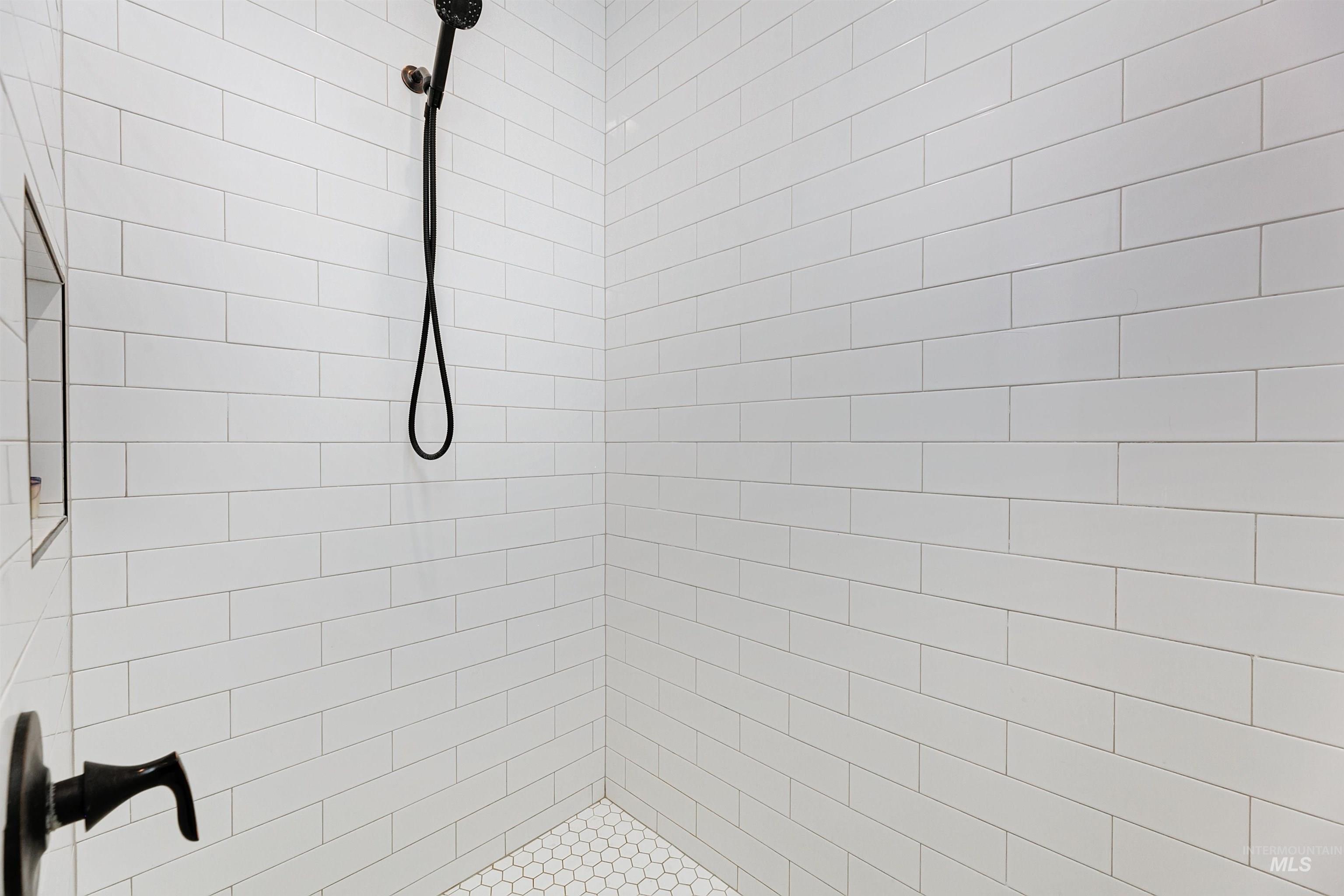 Sleek en-suite walk-in shower with floor to ceiling tile.