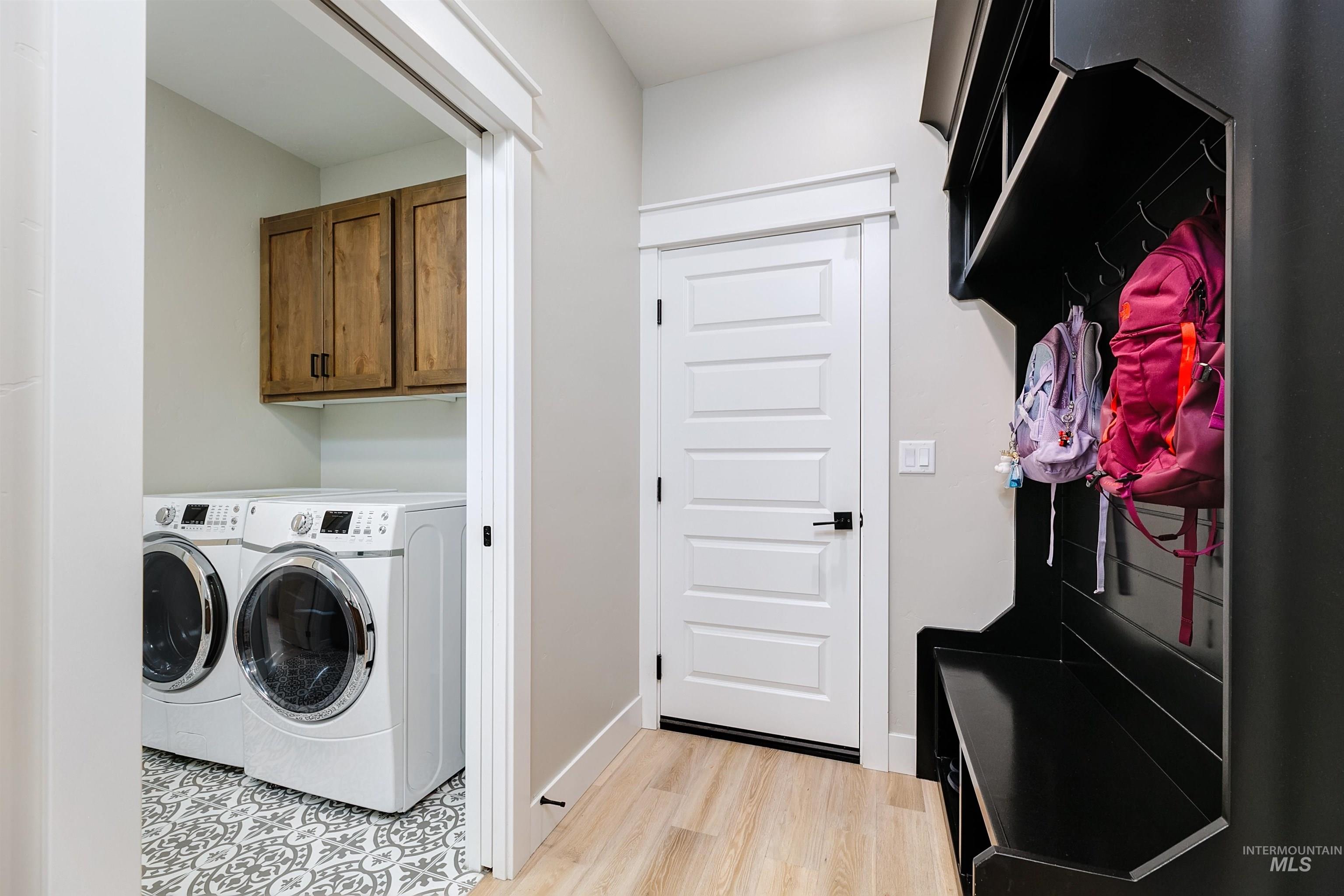 Laundry room with separate washer and dryer, light wood finished floors, and cabinet space