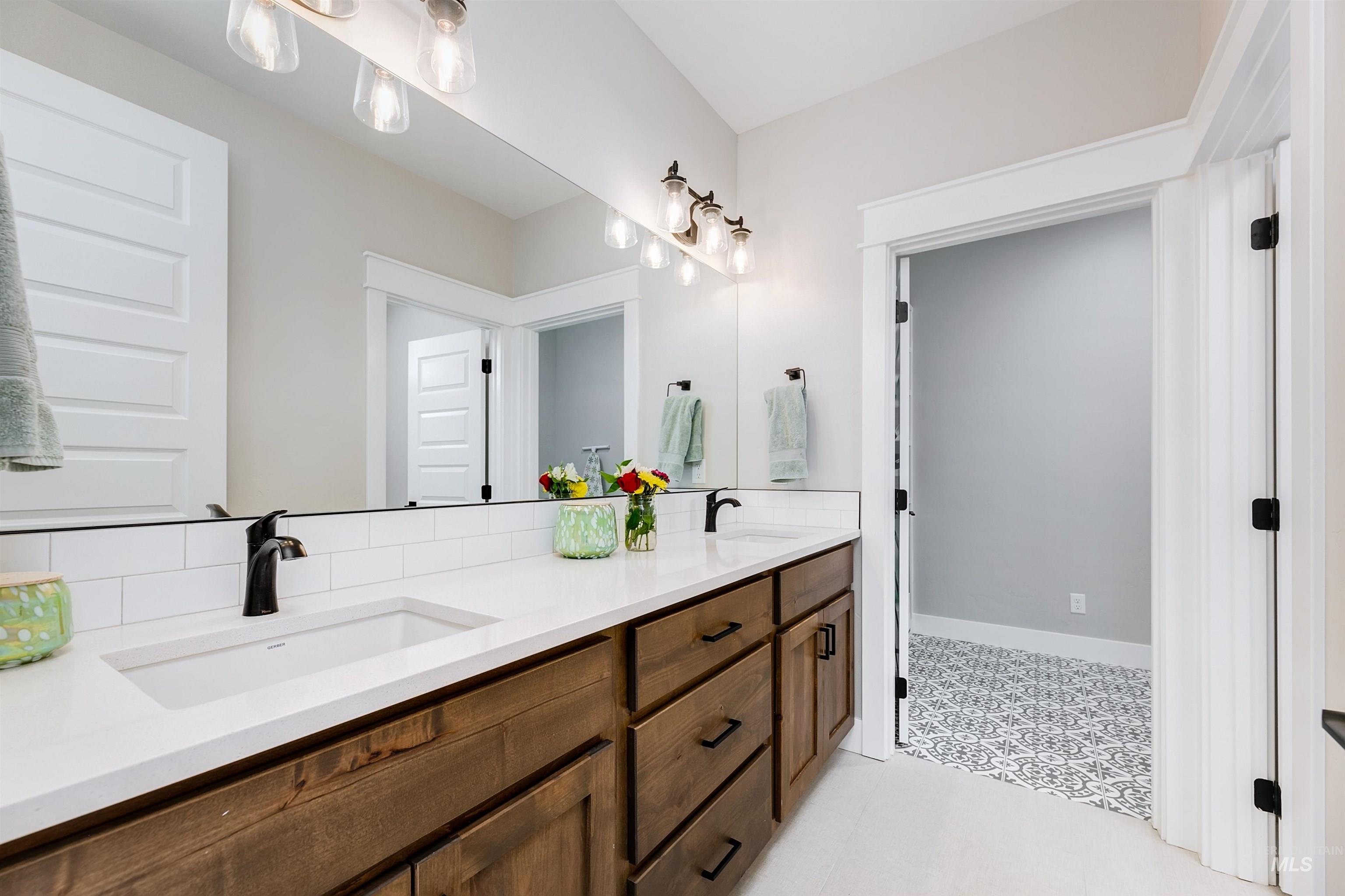 Full bathroom featuring double vanity, tile patterned floors, and quartz countertops.