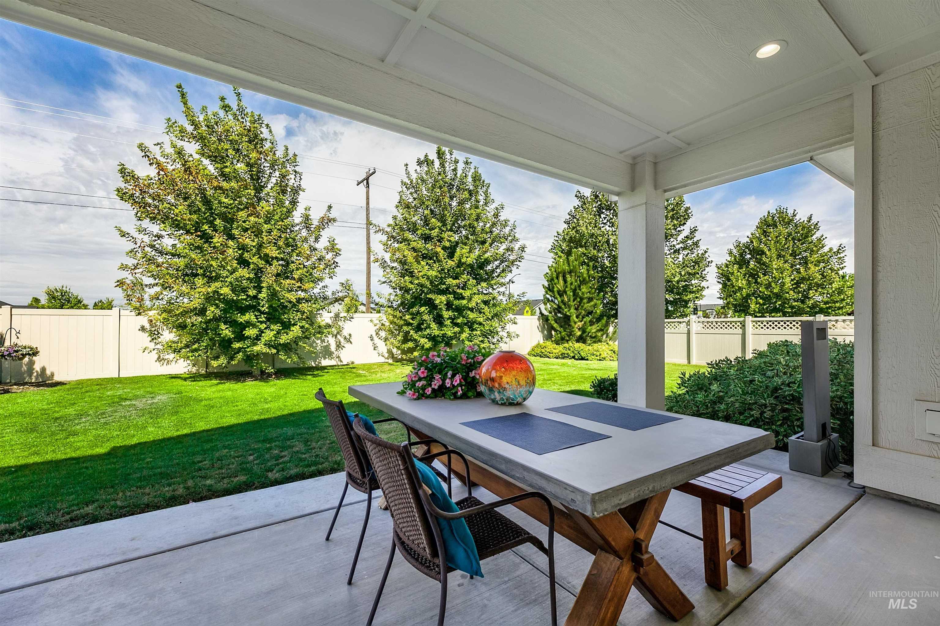 Large, fenced backyard featuring outdoor dining area, low maintenance landscaping, and pocket patio.
