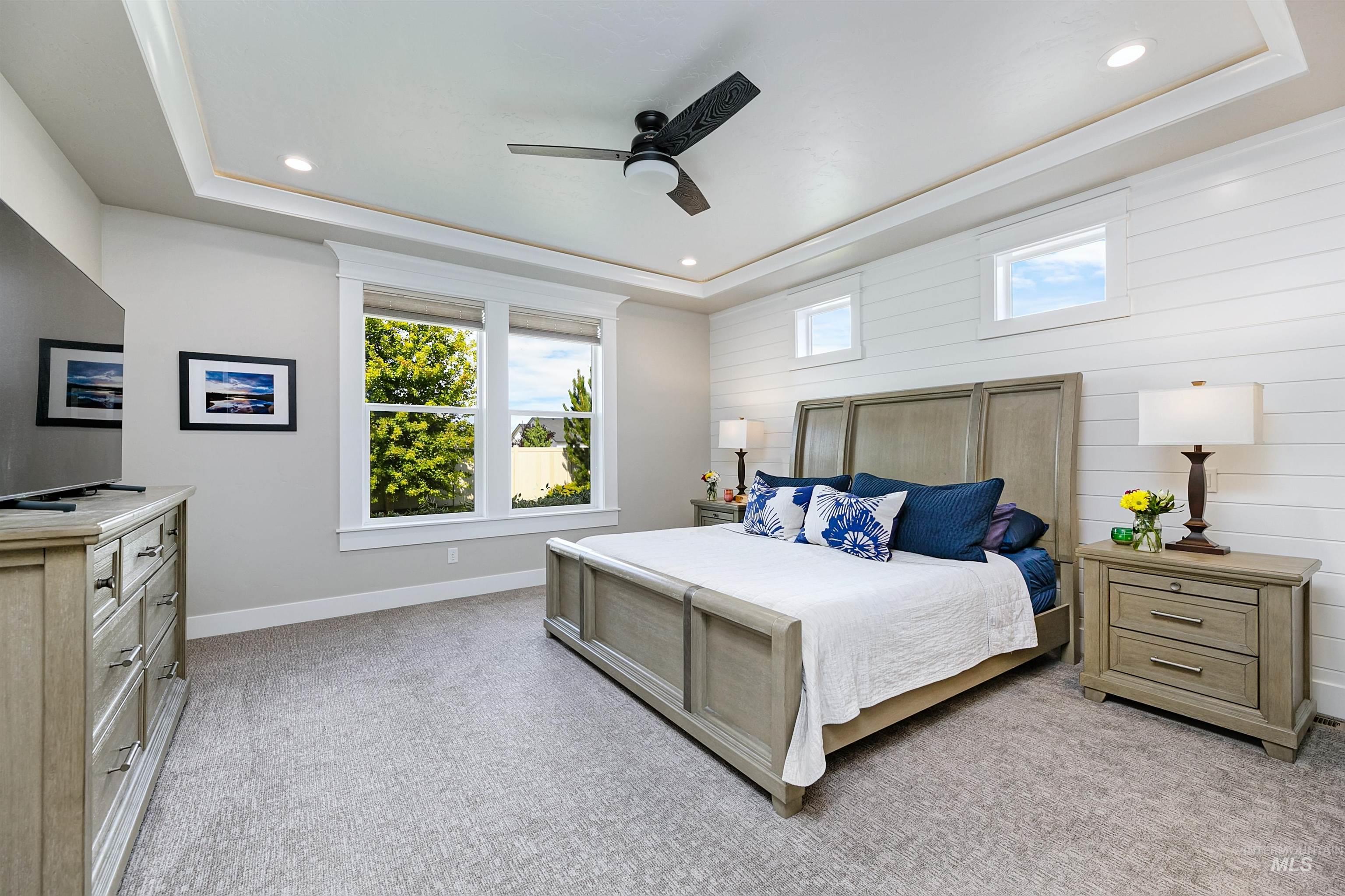 Large downstairs primary suite on main level, featuring beautiful tray ceilings and abundant natural light.