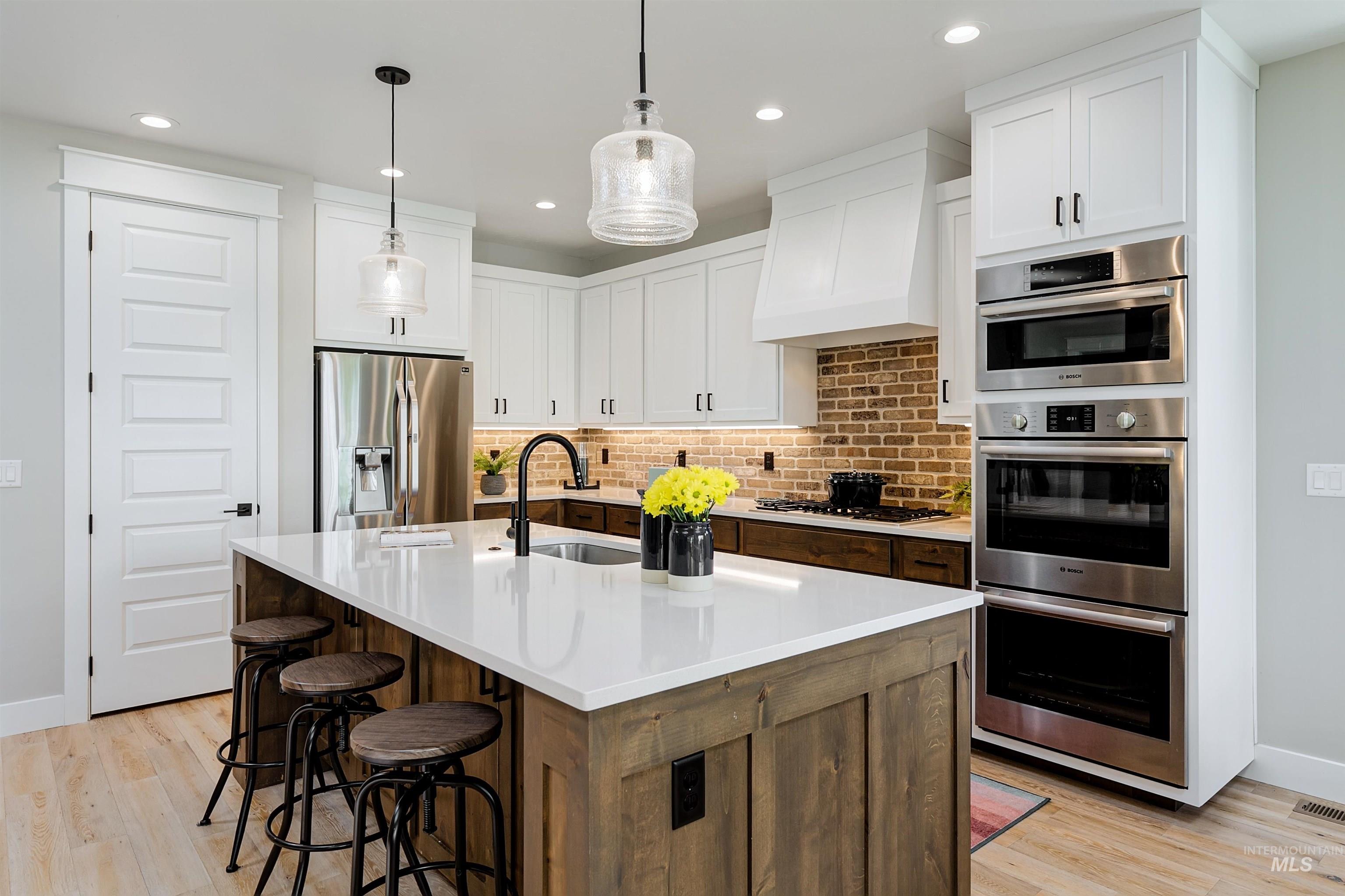 Light infused kitchen featuring upgraded stainless-steel appliances, slab quartz counter-tops, & striking kitchen island. Pantry includes spacious appliance shelf and room galore!