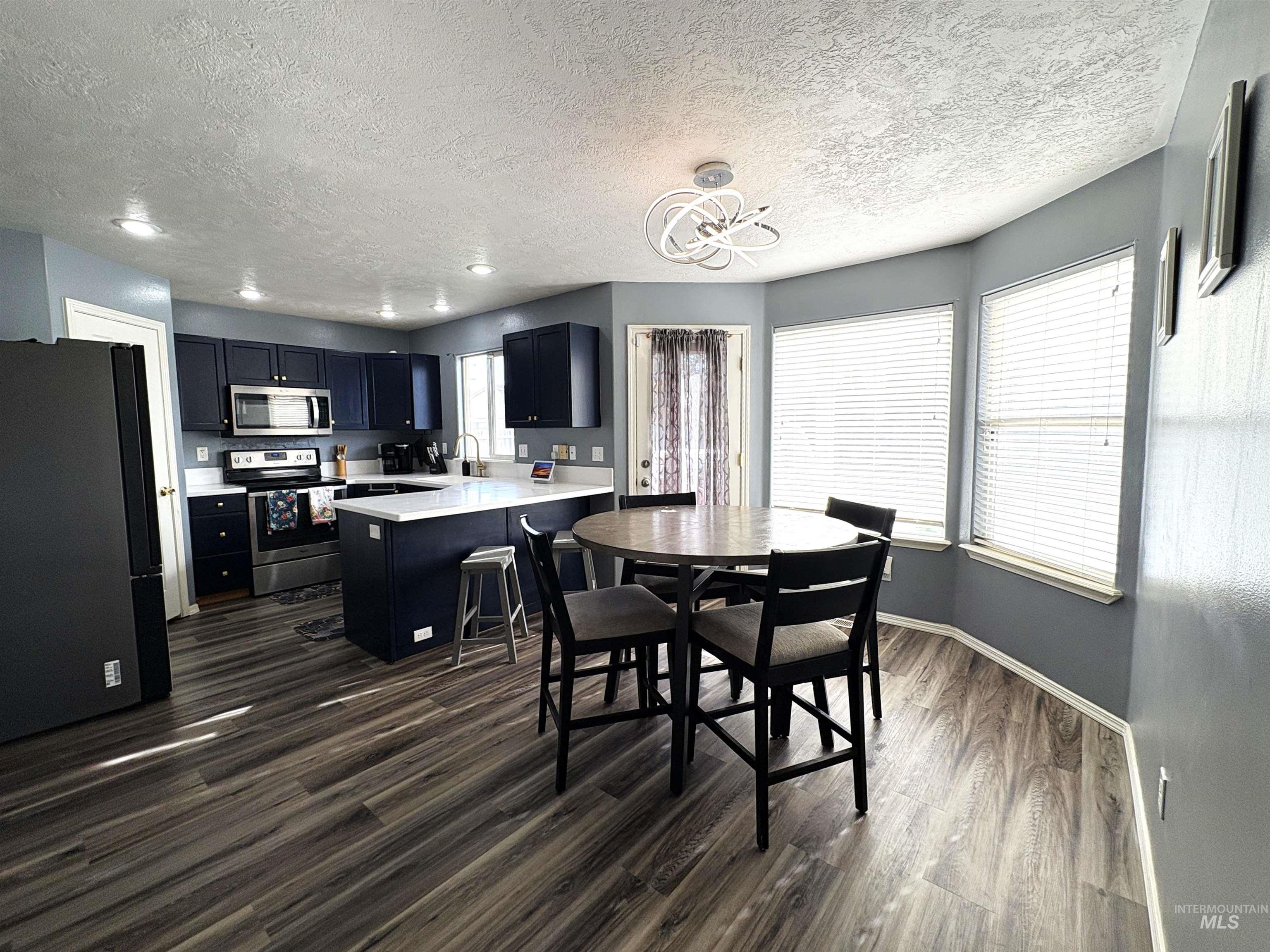 Dining room featuring dark wood finished floors, a textured ceiling, a chandelier, and recessed lighting