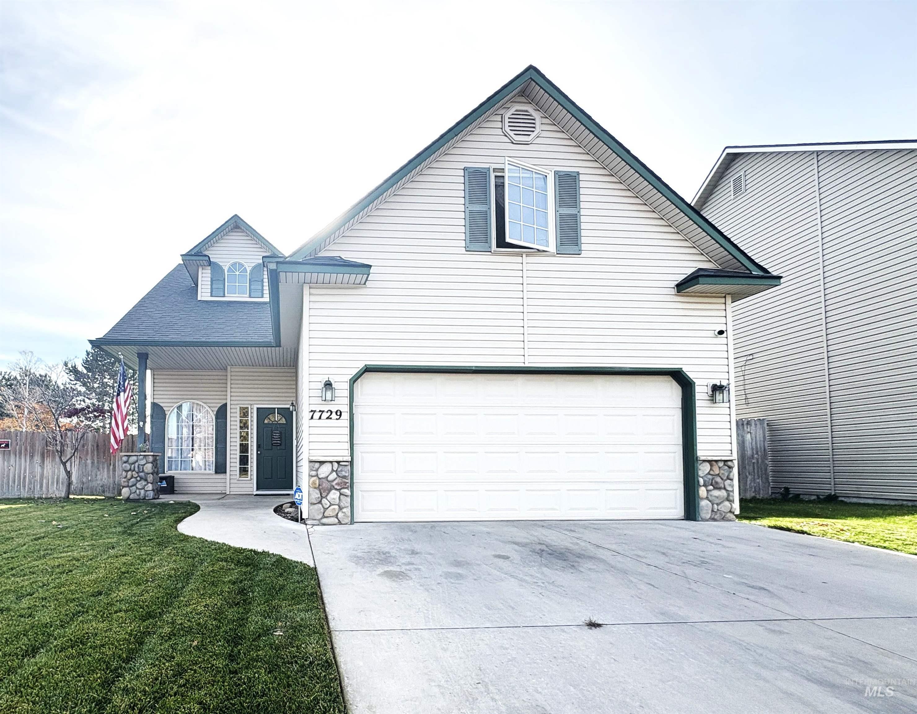 Traditional-style home with stone siding, covered porch, concrete driveway, and an attached garage